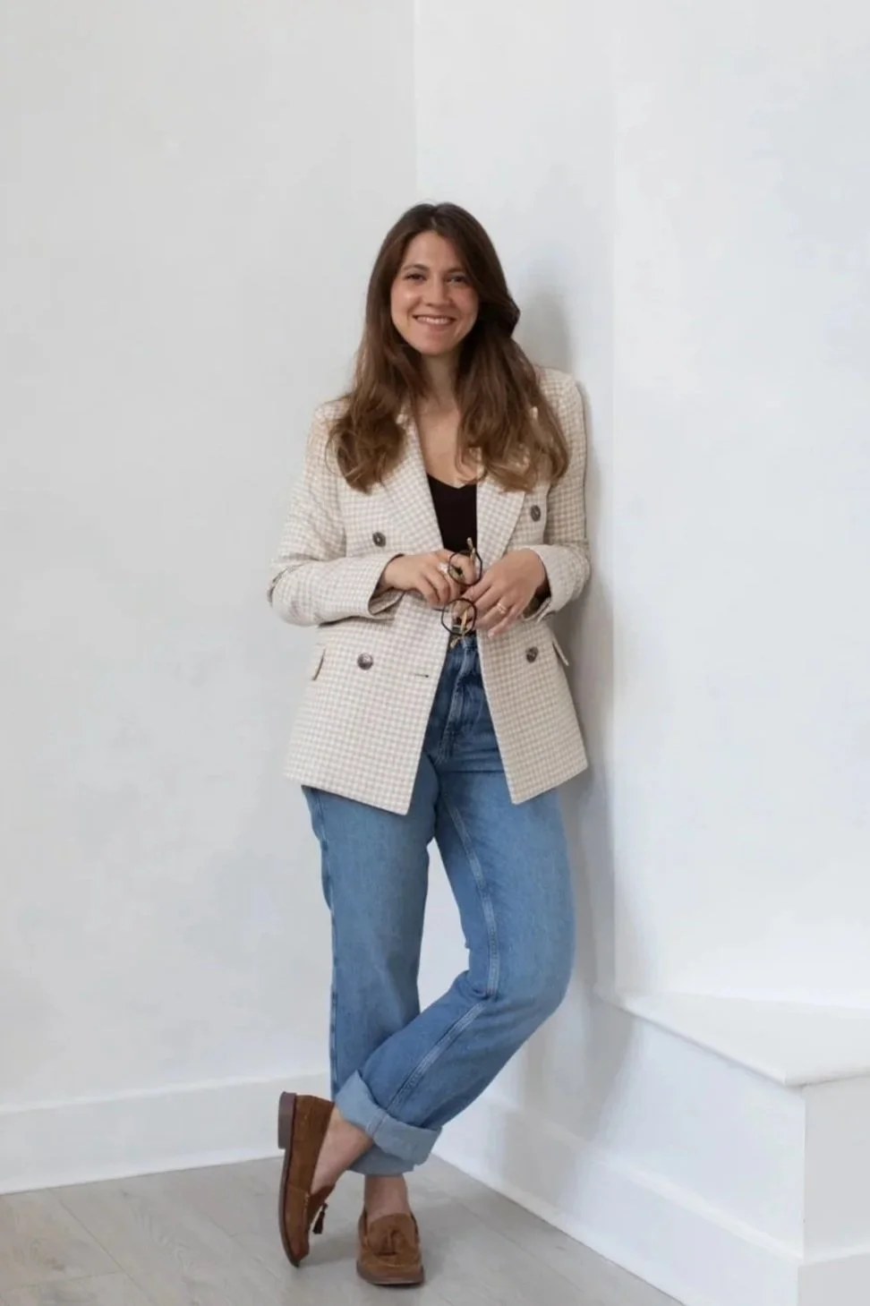 Nergis Yuksel, an SEO strategist for wedding businesses, leaning on a wall and smiling at a camera