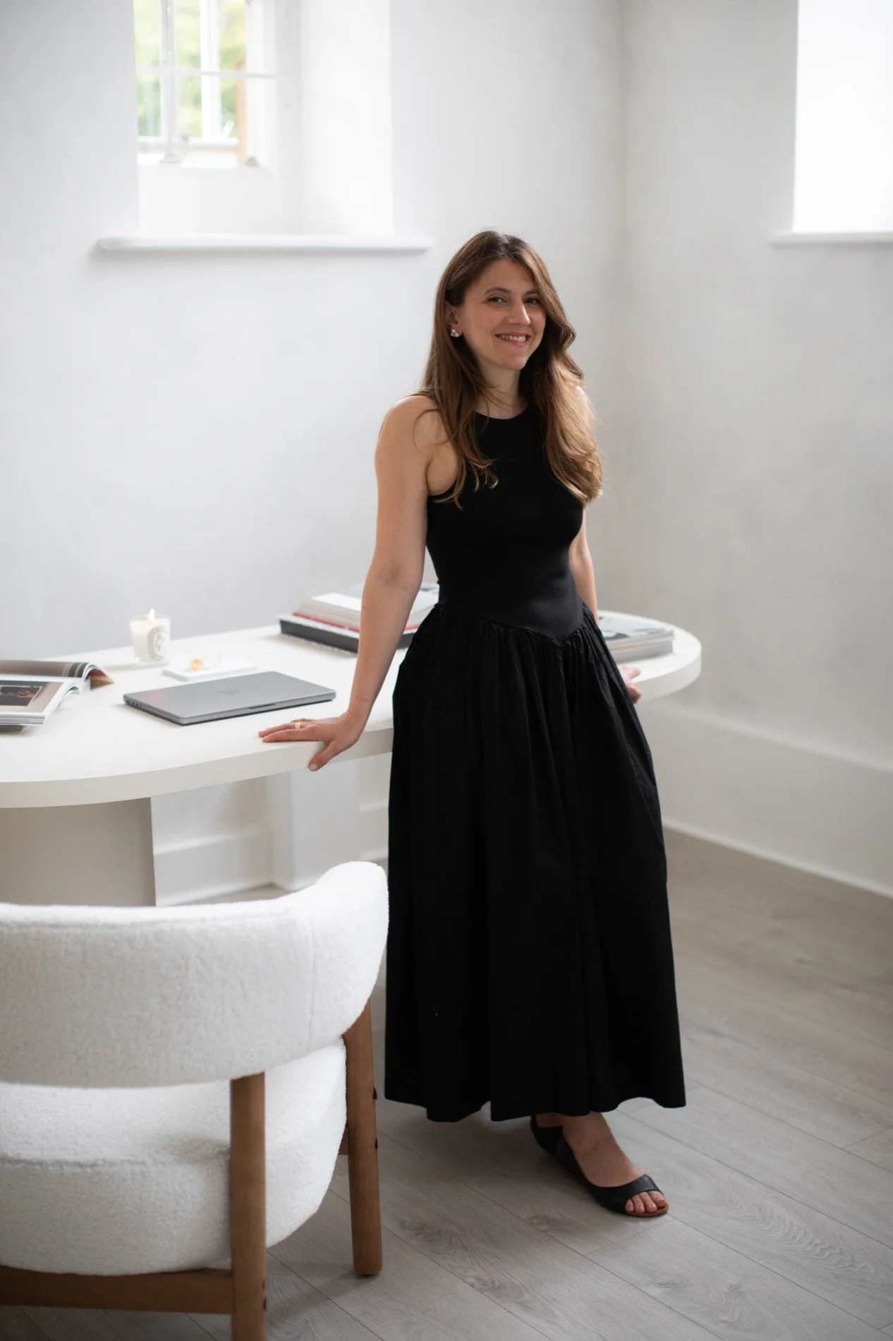 Business portrait of Nergis Yuksel, leaning on her desk and smiling