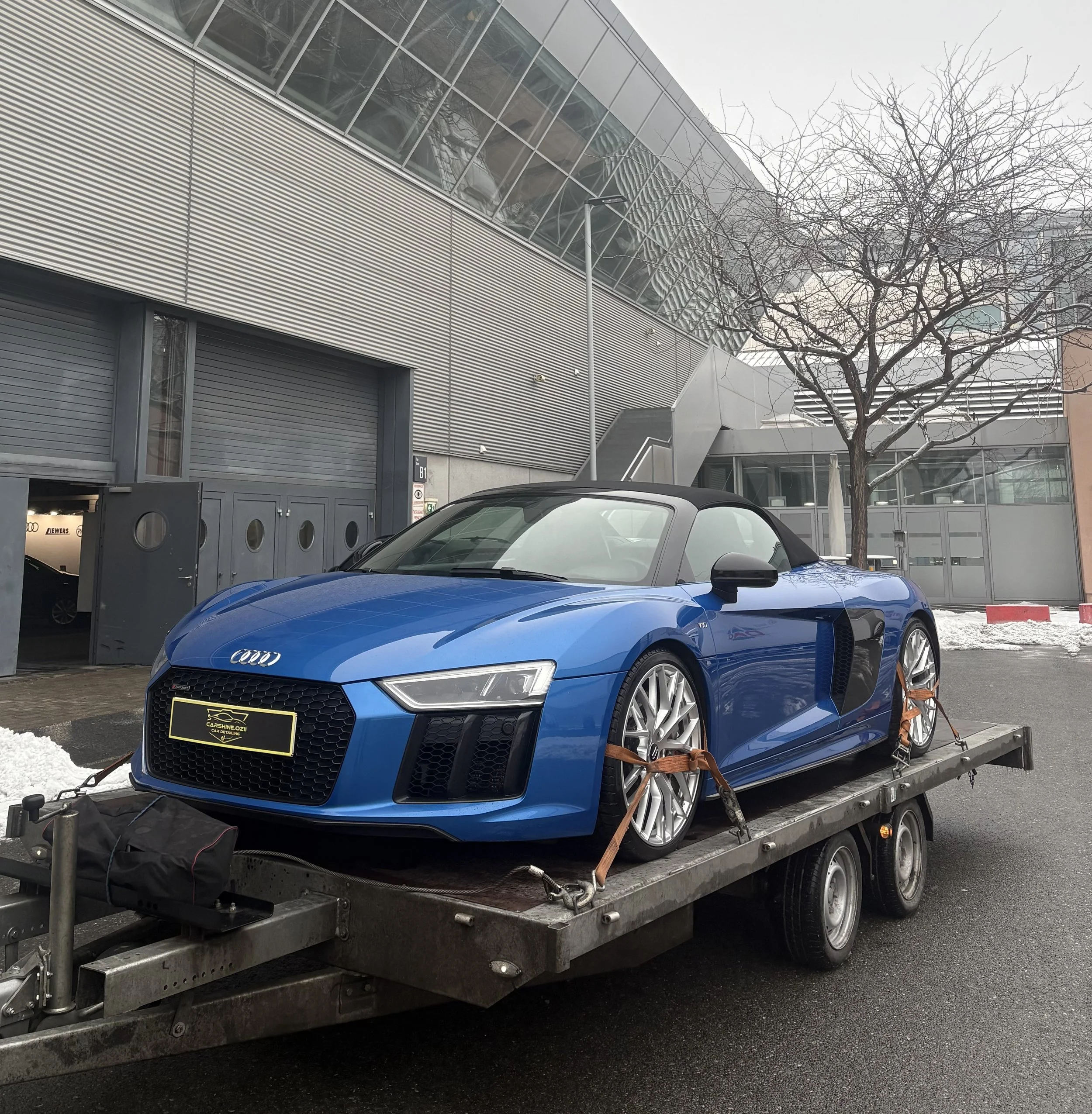 Ein blauer Audi Sportwagen wird mit einem Abschleppwagen transportiert.