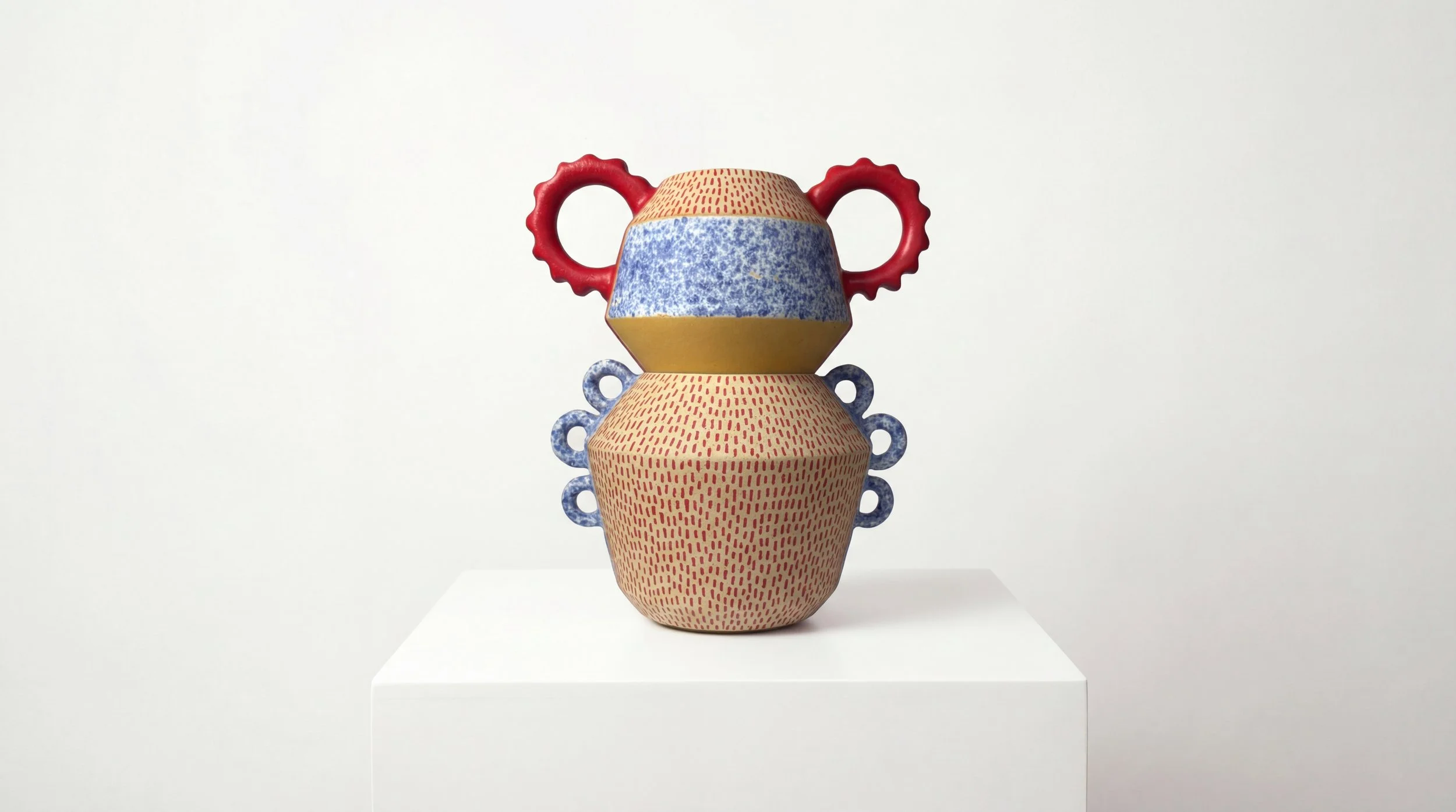 A colorful stacked ceramic sculpture with three interconnected parts on a white pedestal against a plain white background.
