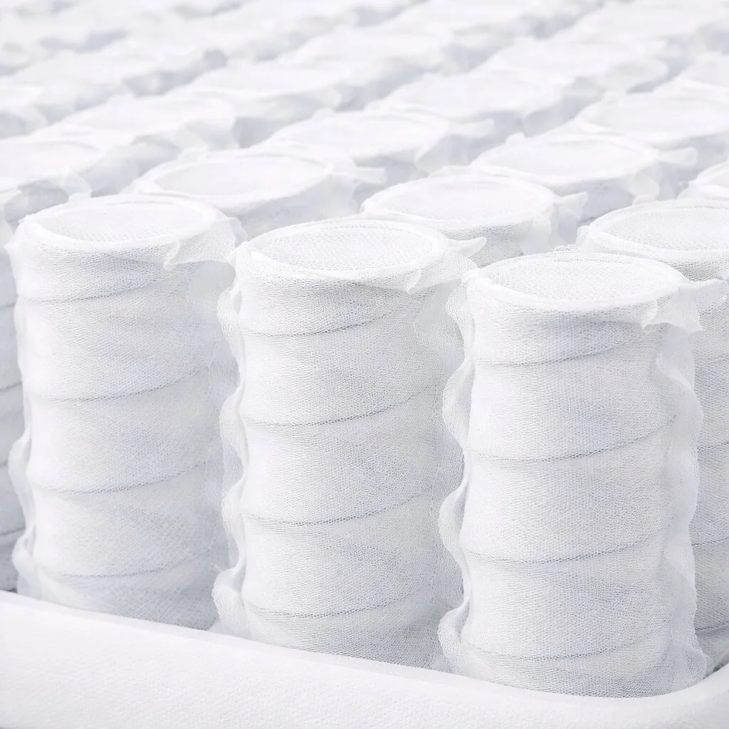 Stacks of white fabric or mesh cylindrical rolls, possibly medical or industrial filters, arranged in rows.