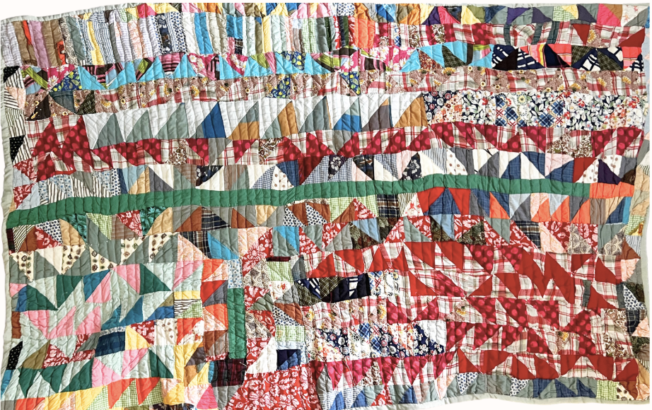 A quilt made of numerous small, colorful fabric patches with various patterns, sewn together in a diagonal, geometric design.