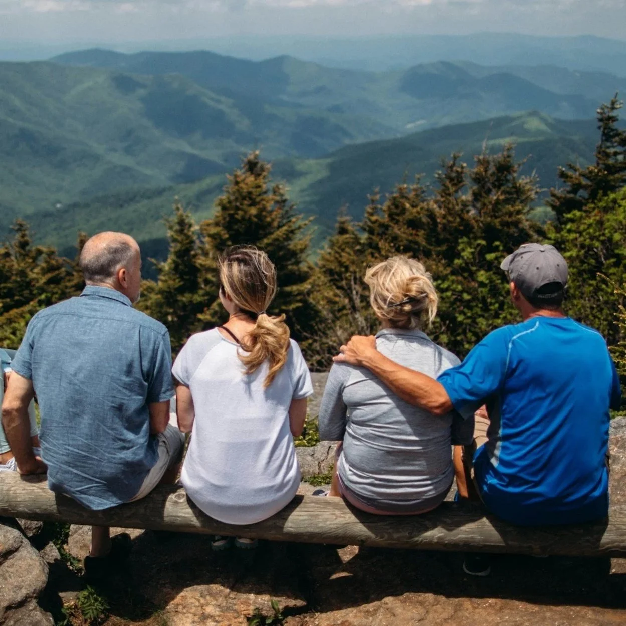 Four adults sitting together overlooking a mountain view, symbolizing family planning and major life transitions.