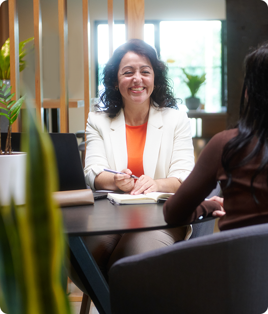 Ana meeting with a client at a table while taking notes, illustrating a healthcare startup CFO providing fractional CFO healthcare support and biotech accounting services | Intellichoice Solutions
