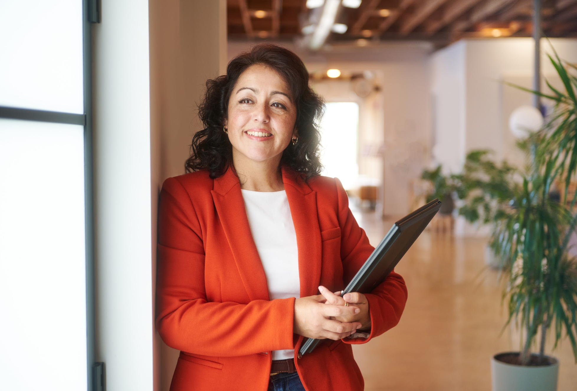 Ana standing and smiling confidently with a tablet, representing a healthcare startup CFO providing fractional CFO healthcare leadership and biotech accounting services | Intellichoice Solutions