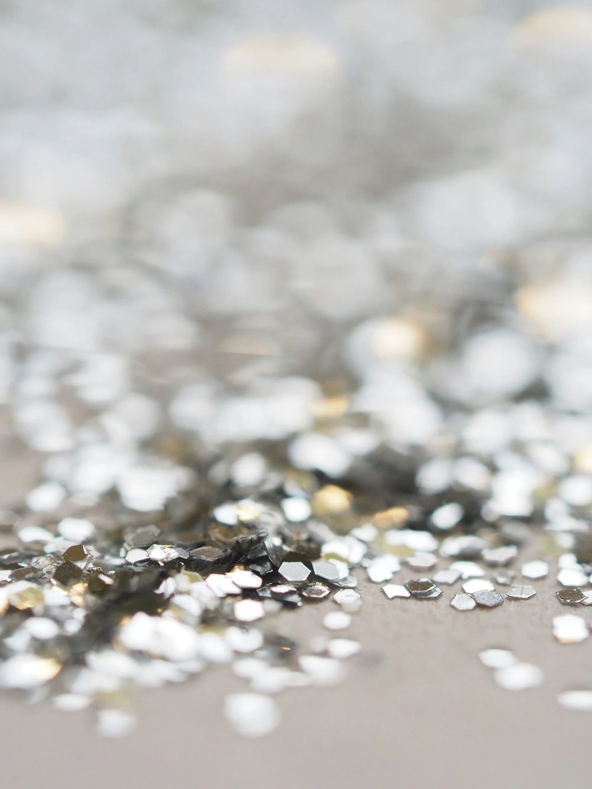 Close-up of metallic hexagonal and circular confetti scattered on a flat surface.