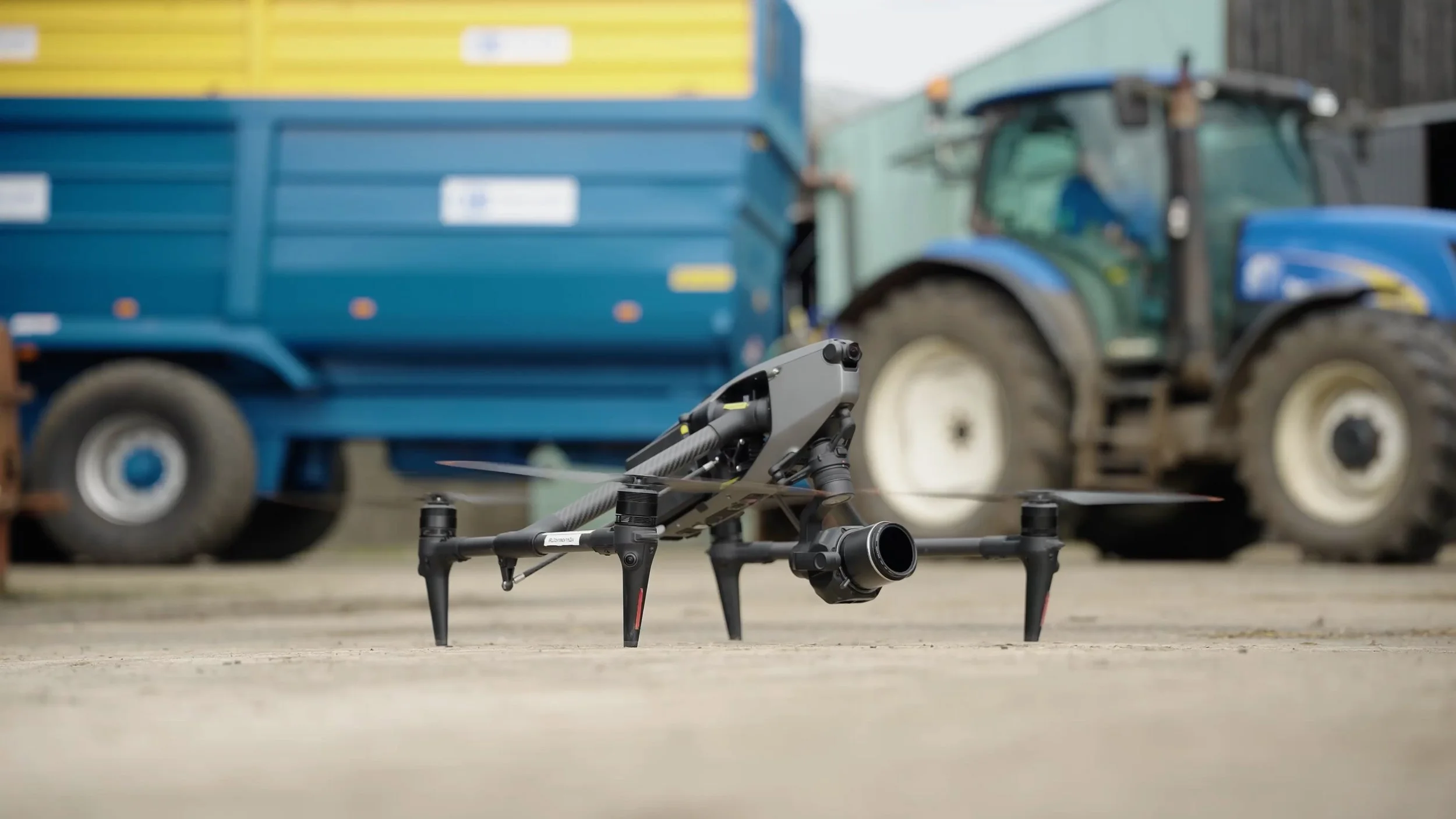 A drone with camera equipment on a concrete surface in front of a blue tractor trailer.