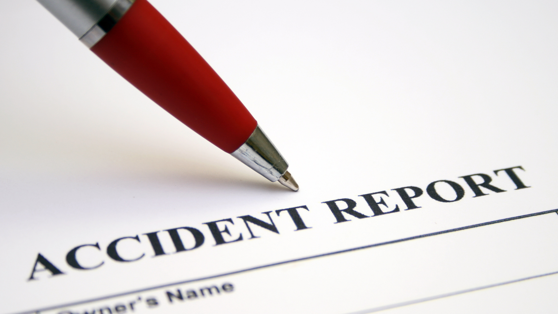 Close-up of a red pen writing on an accident report form.