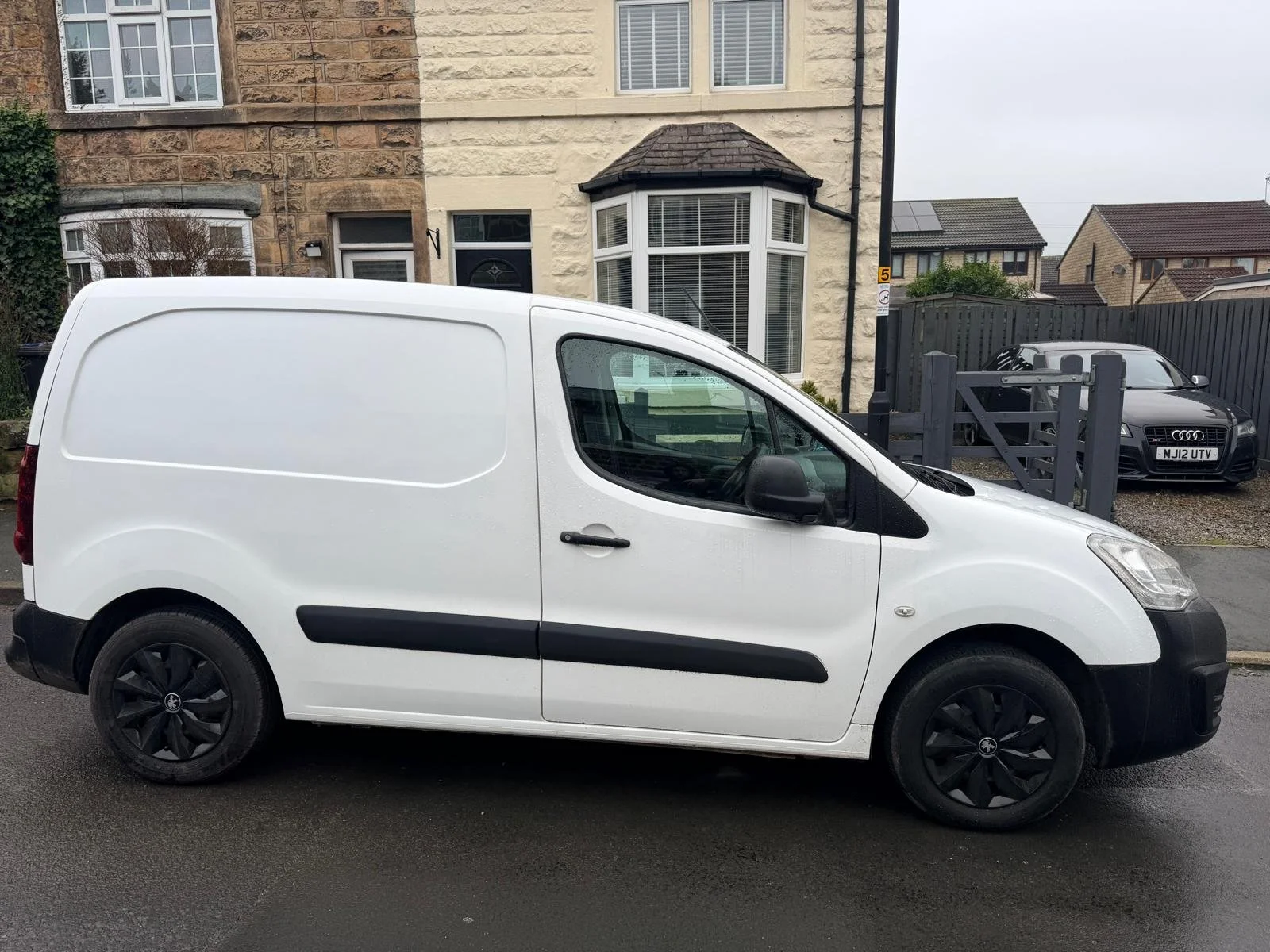 White panel van parked on the street in front of residential houses.