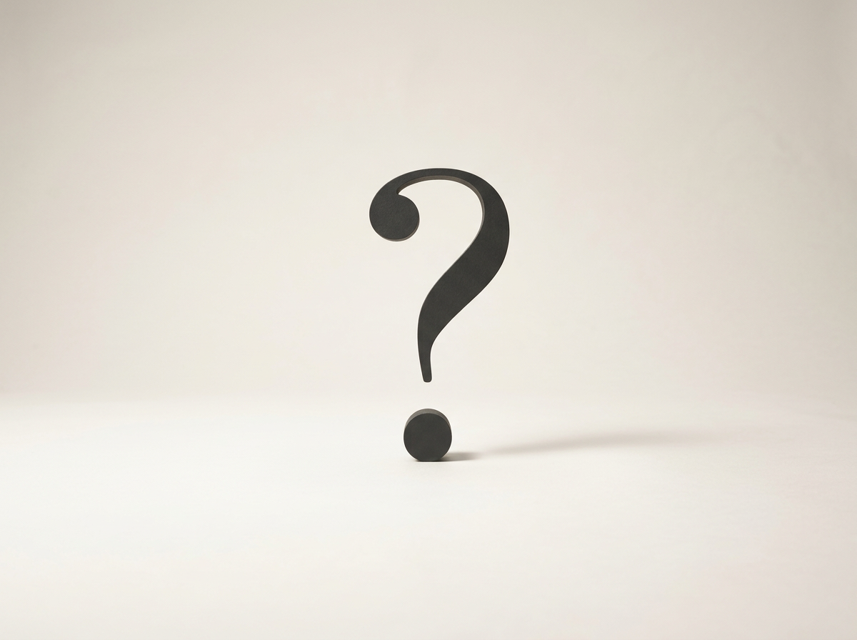 A black question mark standing on a white surface against a white background.