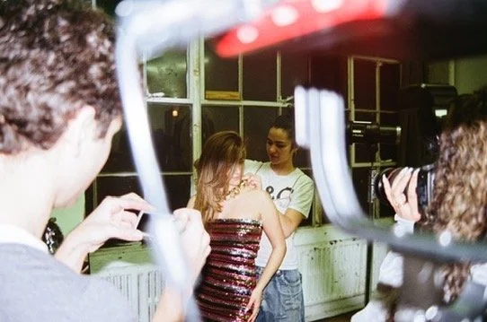 People taking photos of a woman in a striped dress in an indoor setting.