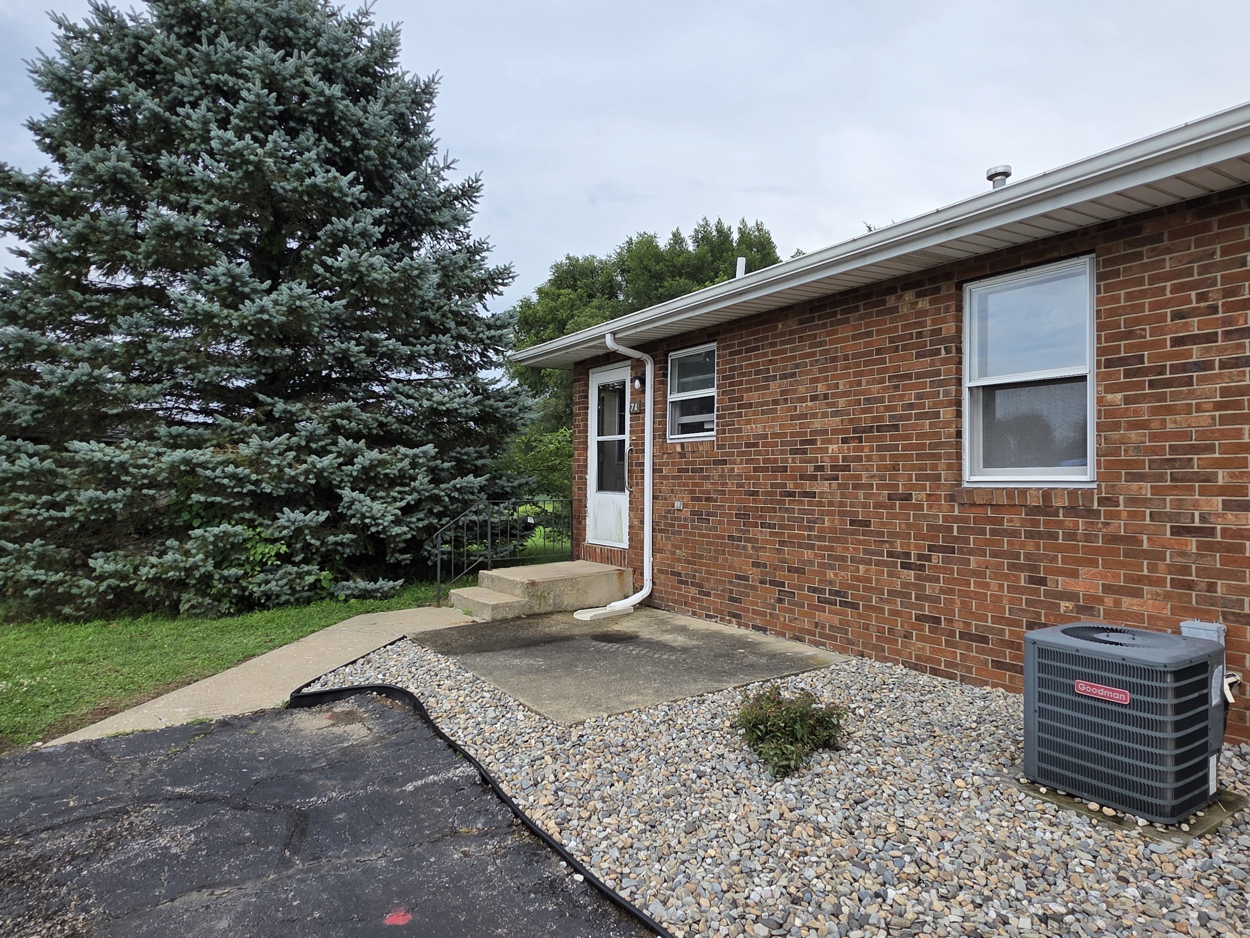 Front exterior of Unit 7A at The Vues in North Liberty, Indiana, a single-story two-bedroom home with private entrance, front walkway and landscaped lawn.