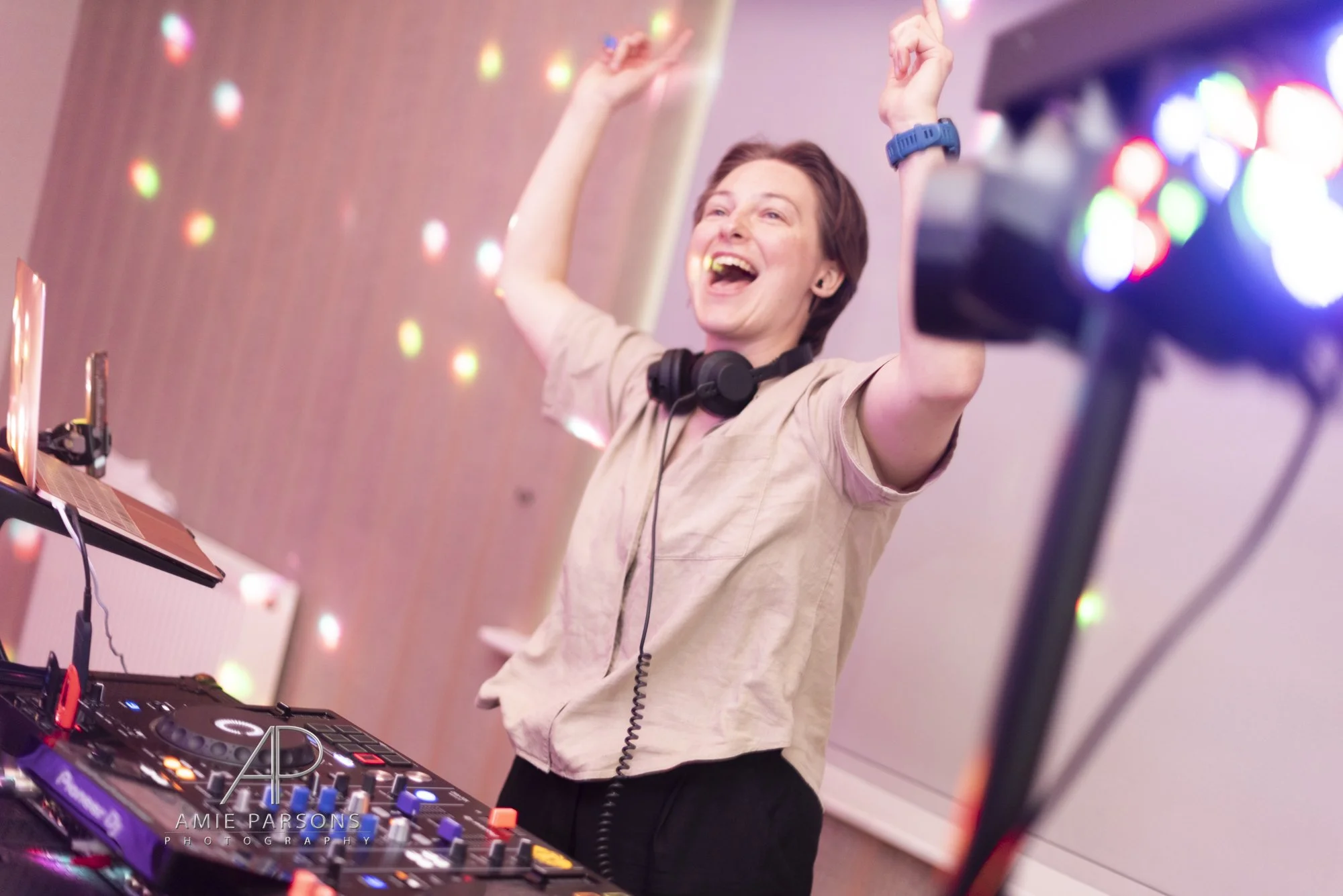 Female DJ has her hands in the air and smiles at her dance floor