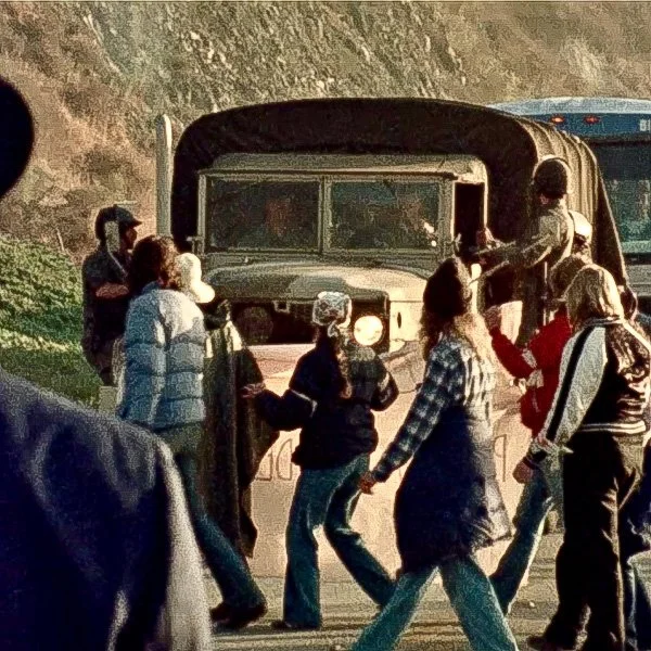 people walk by military vehicle