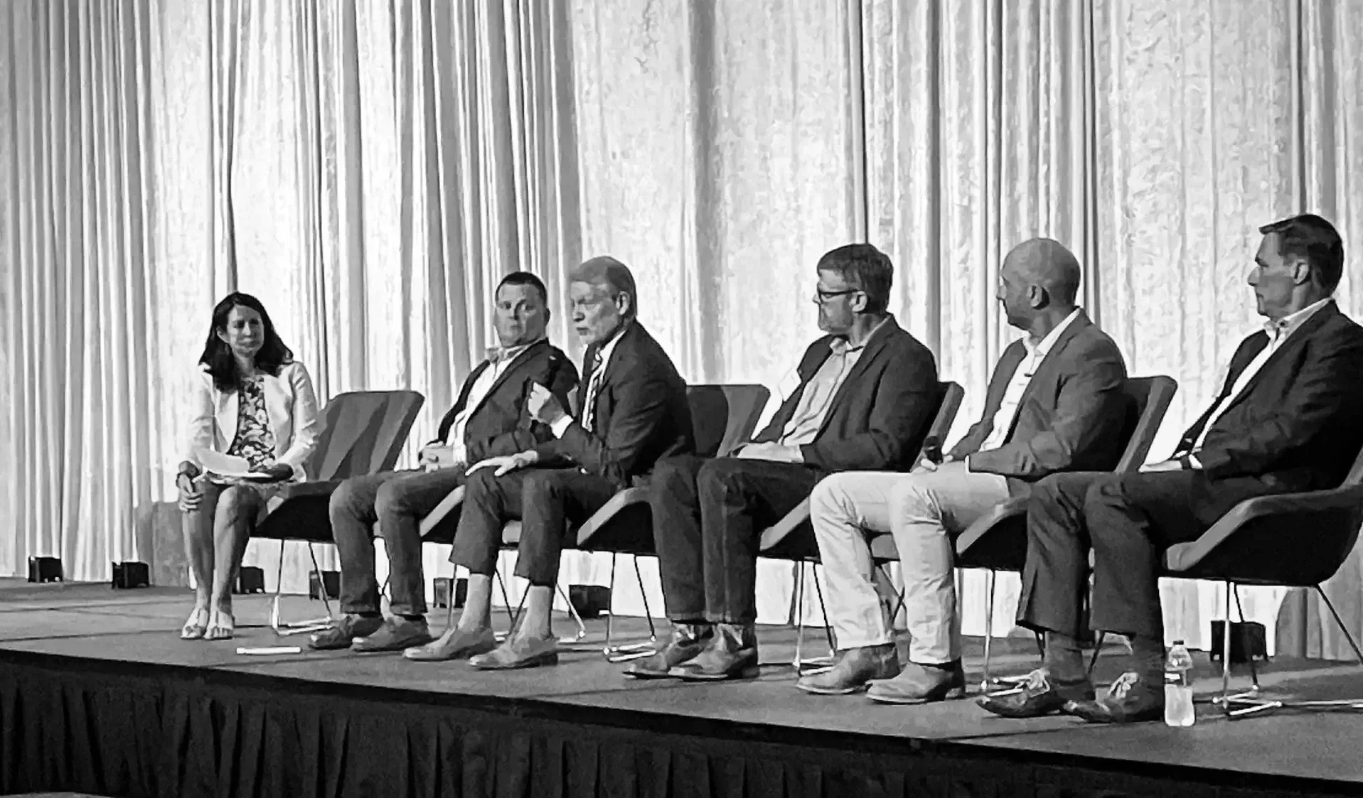 Group of men talking on stage at South Dakota Economic Outlook Seminar.
