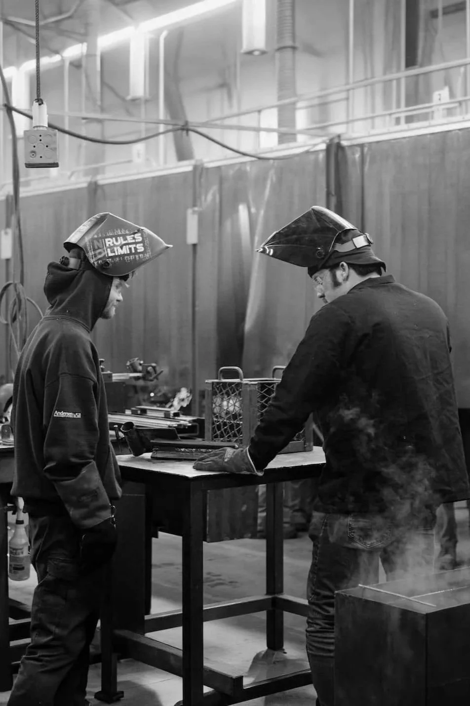 Two men in welding hoods talking.