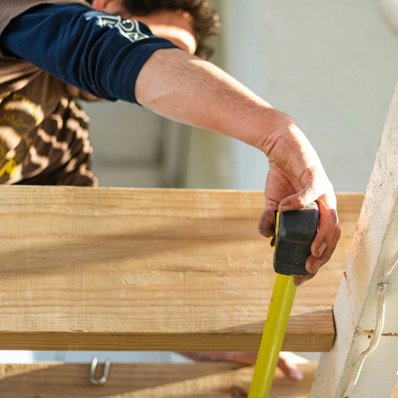 Image of a construction worker measuring a beam