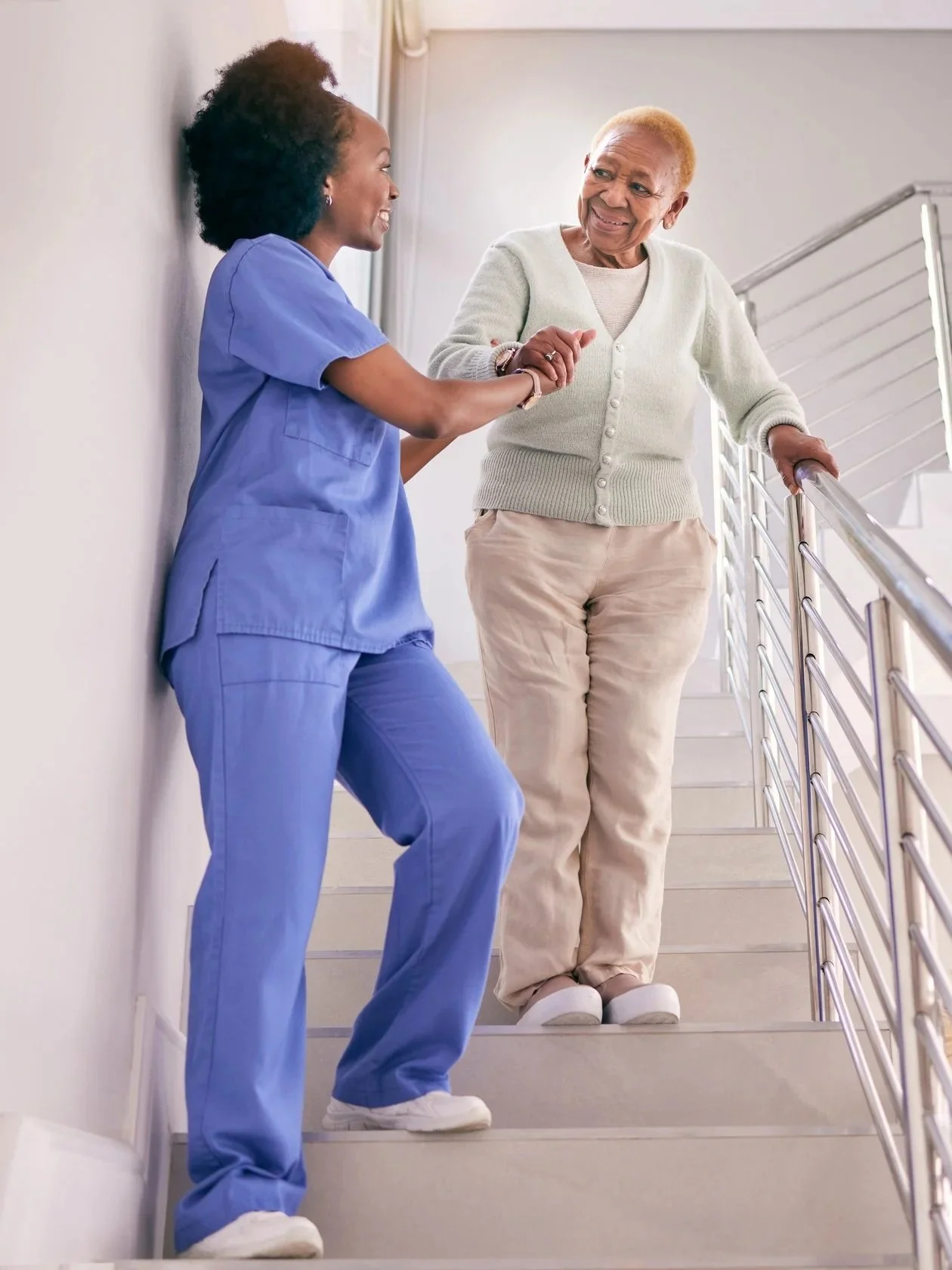 Caregiver assisting an older adult while walking down stairs.