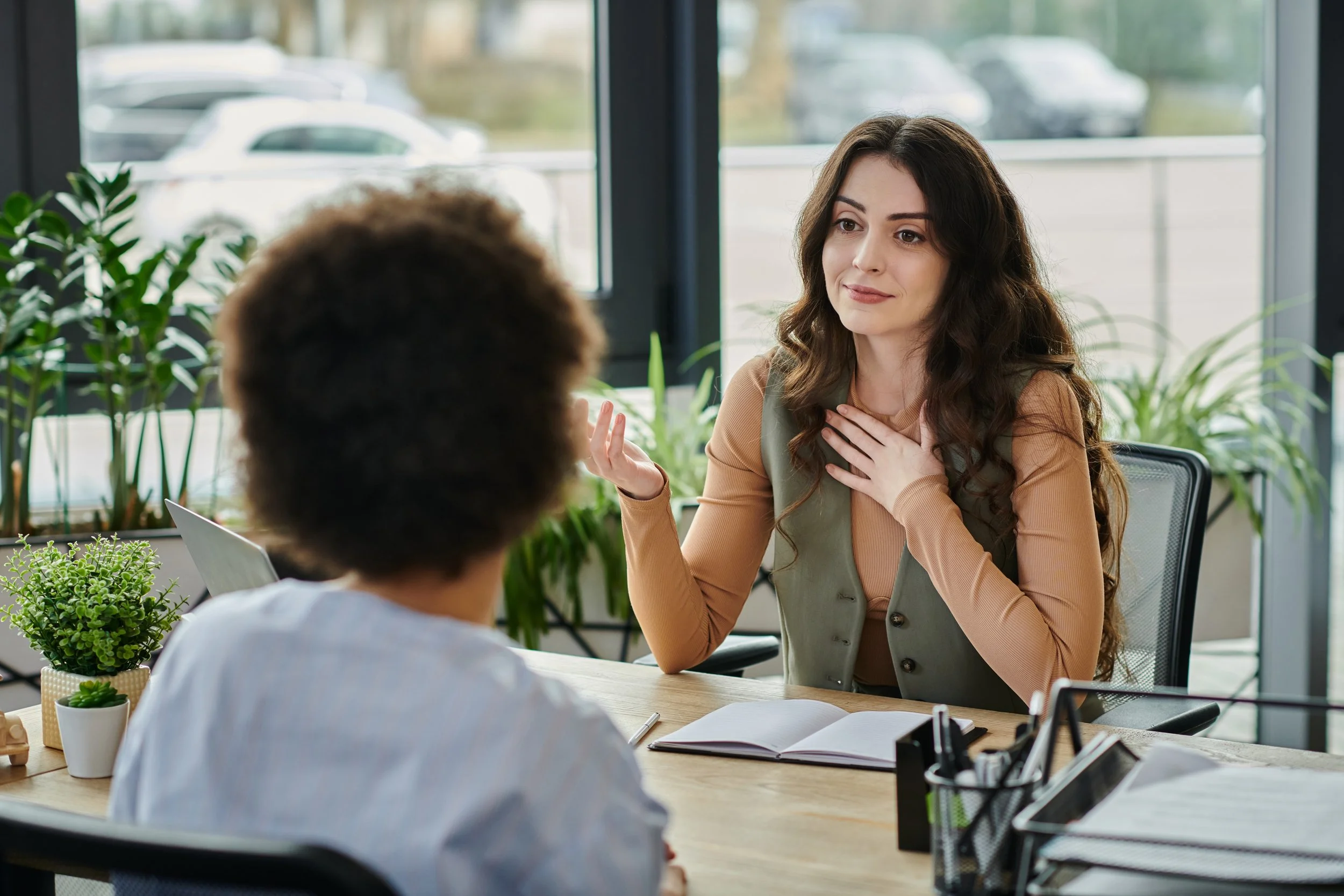 Two people having a conversation across a table in an office.