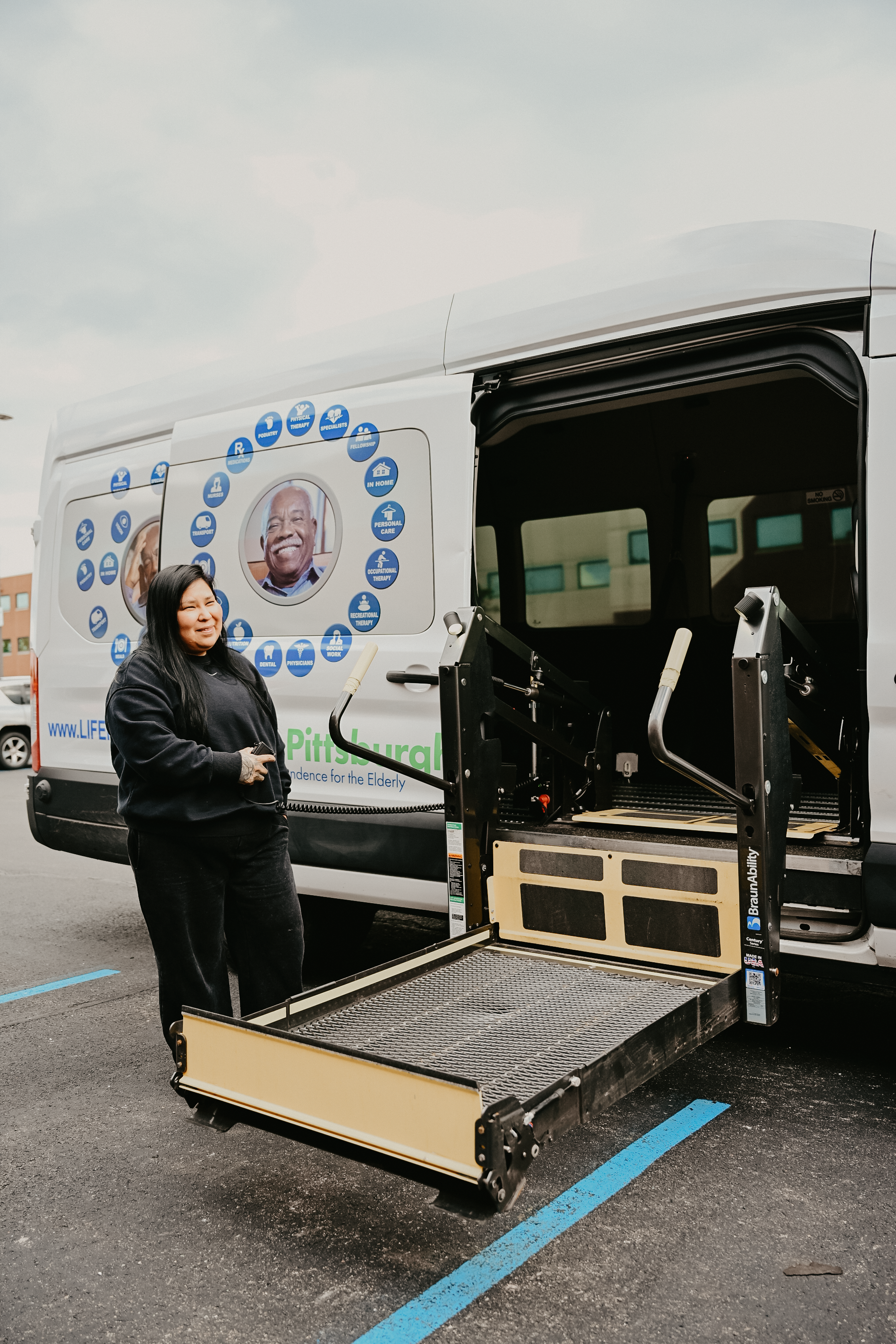 LIFE Pittsburgh wheelchair-accessible transportation van with its lift extended.. The vehicle has an open lift platform, suggesting it is used for mobility assistance.