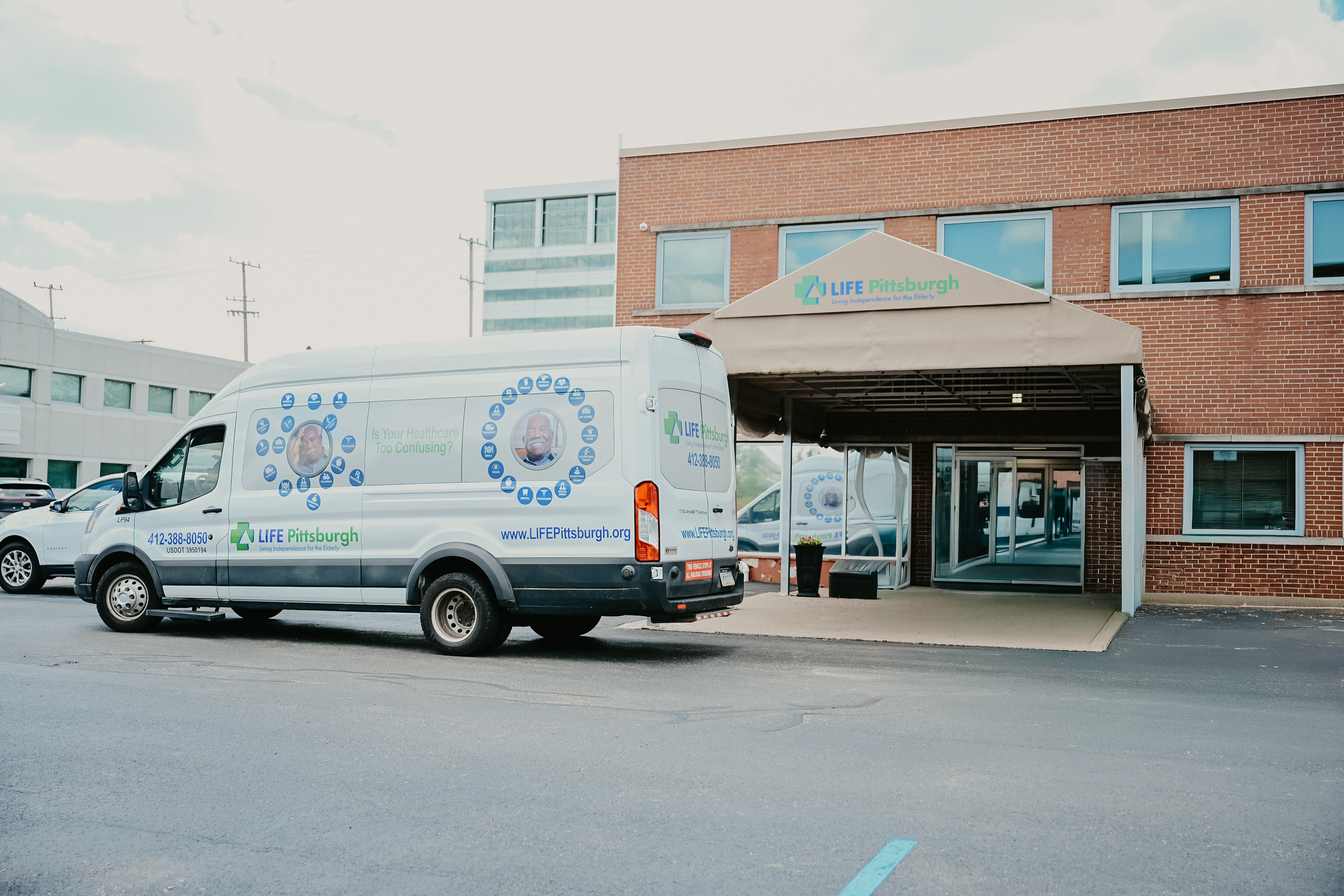 Mobile healthcare van parked outside a building labeled LIFE Pittsburgh with a canopy entrance, in a parking lot.