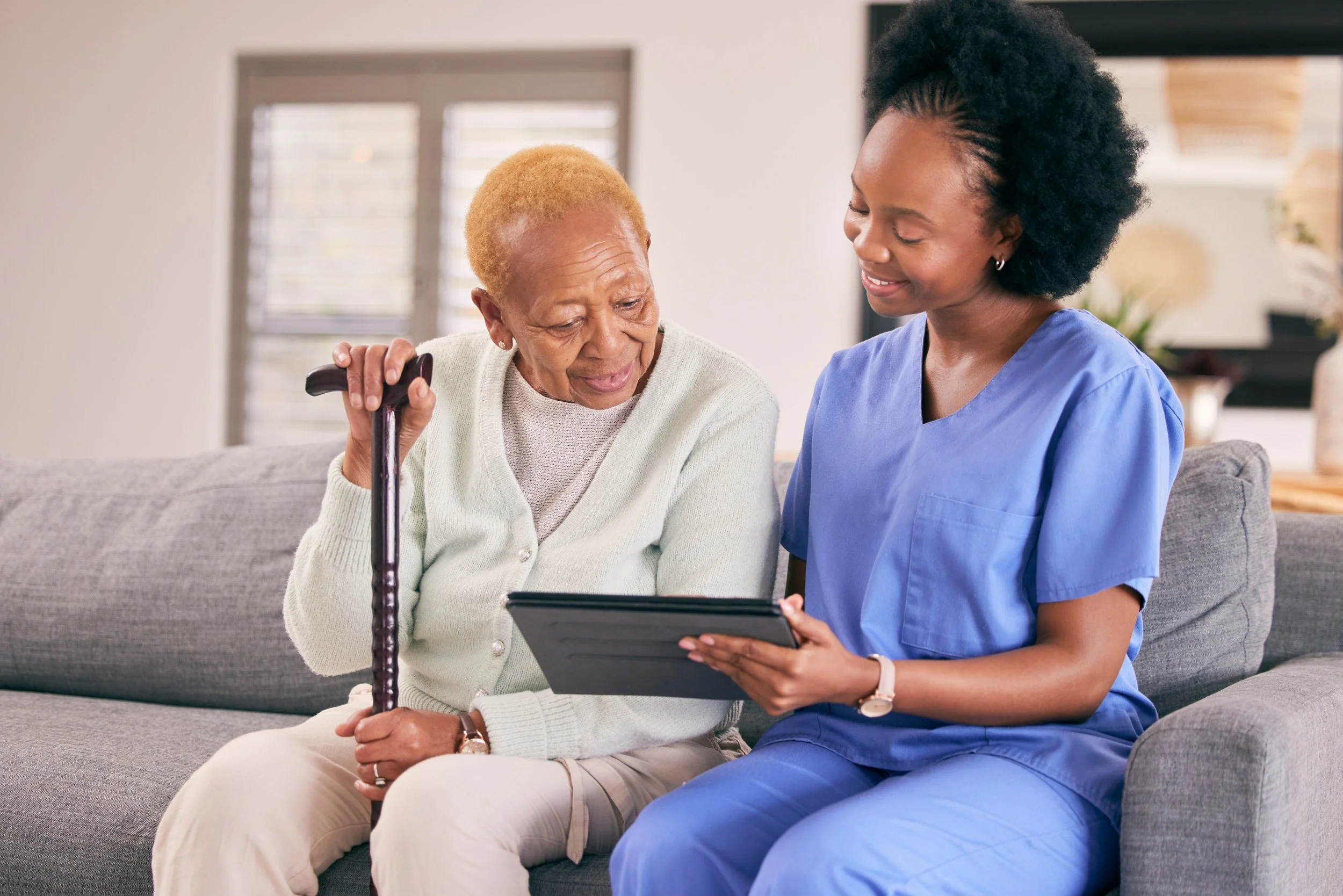 Caregiver and older adult reviewing information together on a tablet or IPAD.