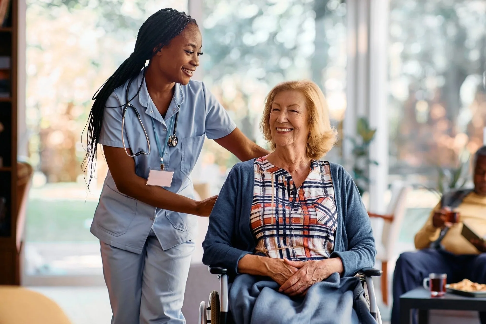 Healthcare professional speaking with an older adult using a wheelchair.