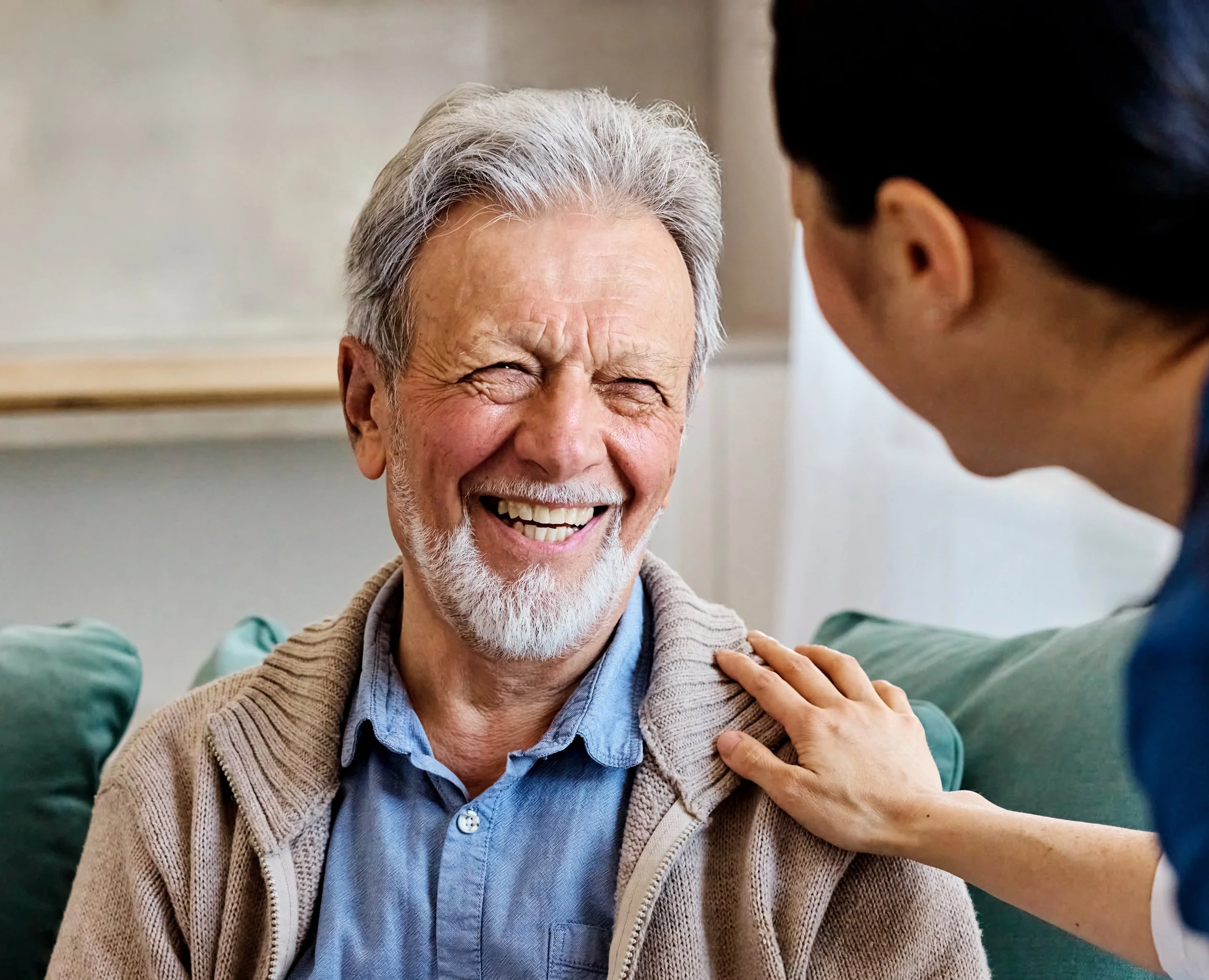 Older adult smiling while receiving support from a caregiver..