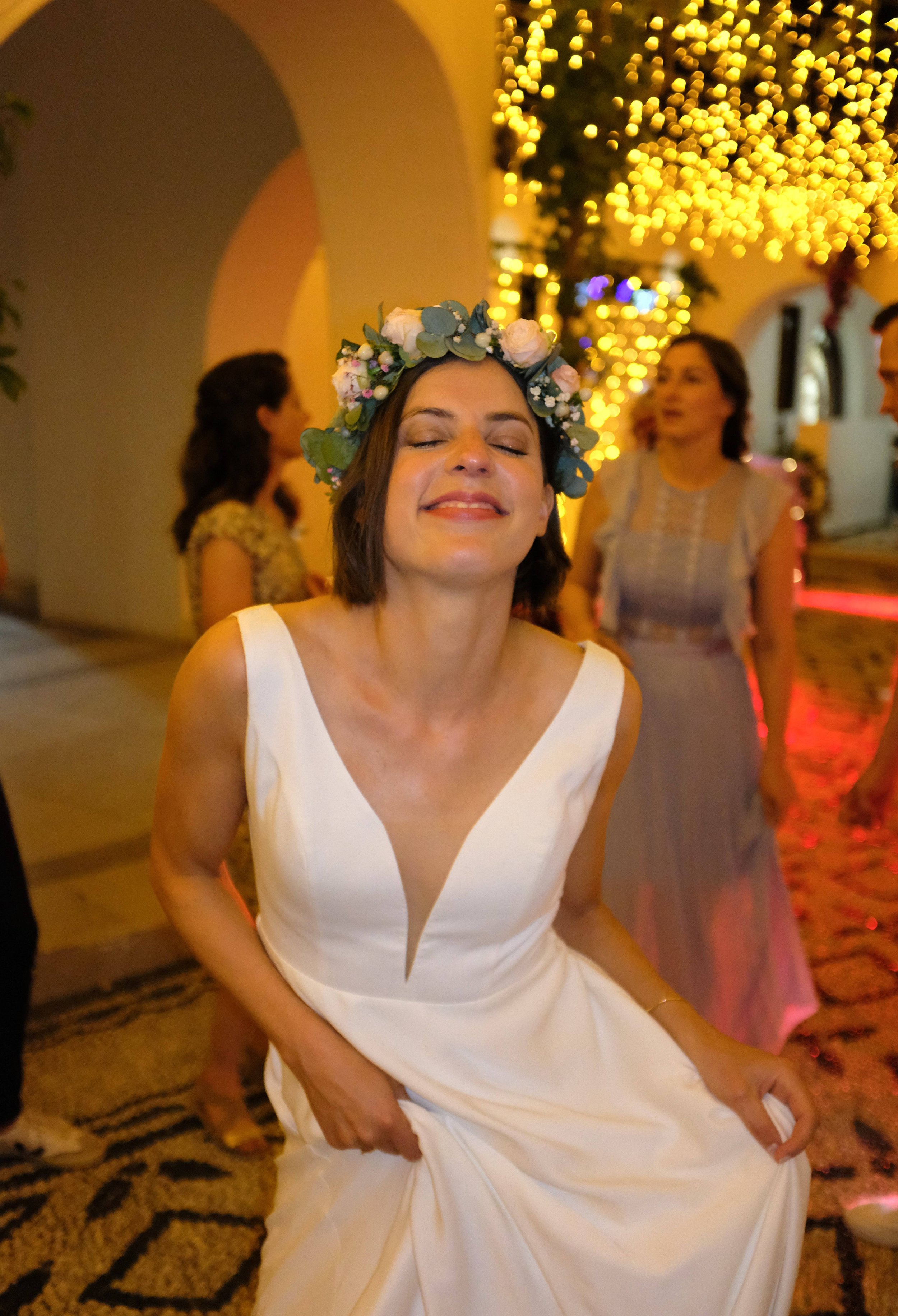 Eine glückliche Frau in einem weißen Brautkleid mit Blütenkranz auf dem Kopf auf einer Party