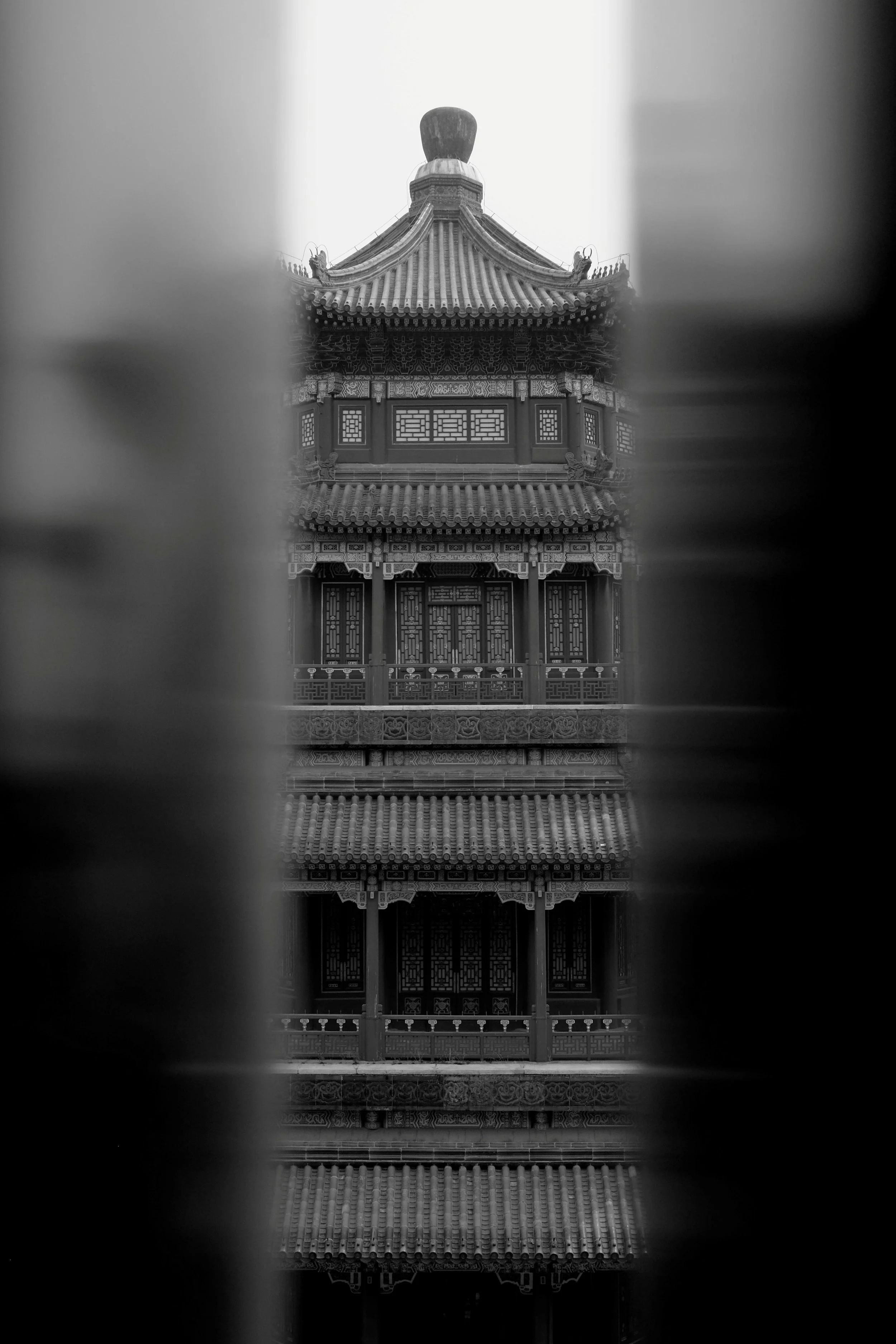 Minimalistische Architekturstudie eines traditionellen chinesischen Tempels in Peking. Der gerahmte Blick durch eine vertikale Öffnung betont die Symmetrie und Detailtiefe. Ein Beispiel für den architektonischen Fokus und das Spiel mit Perspektiven b