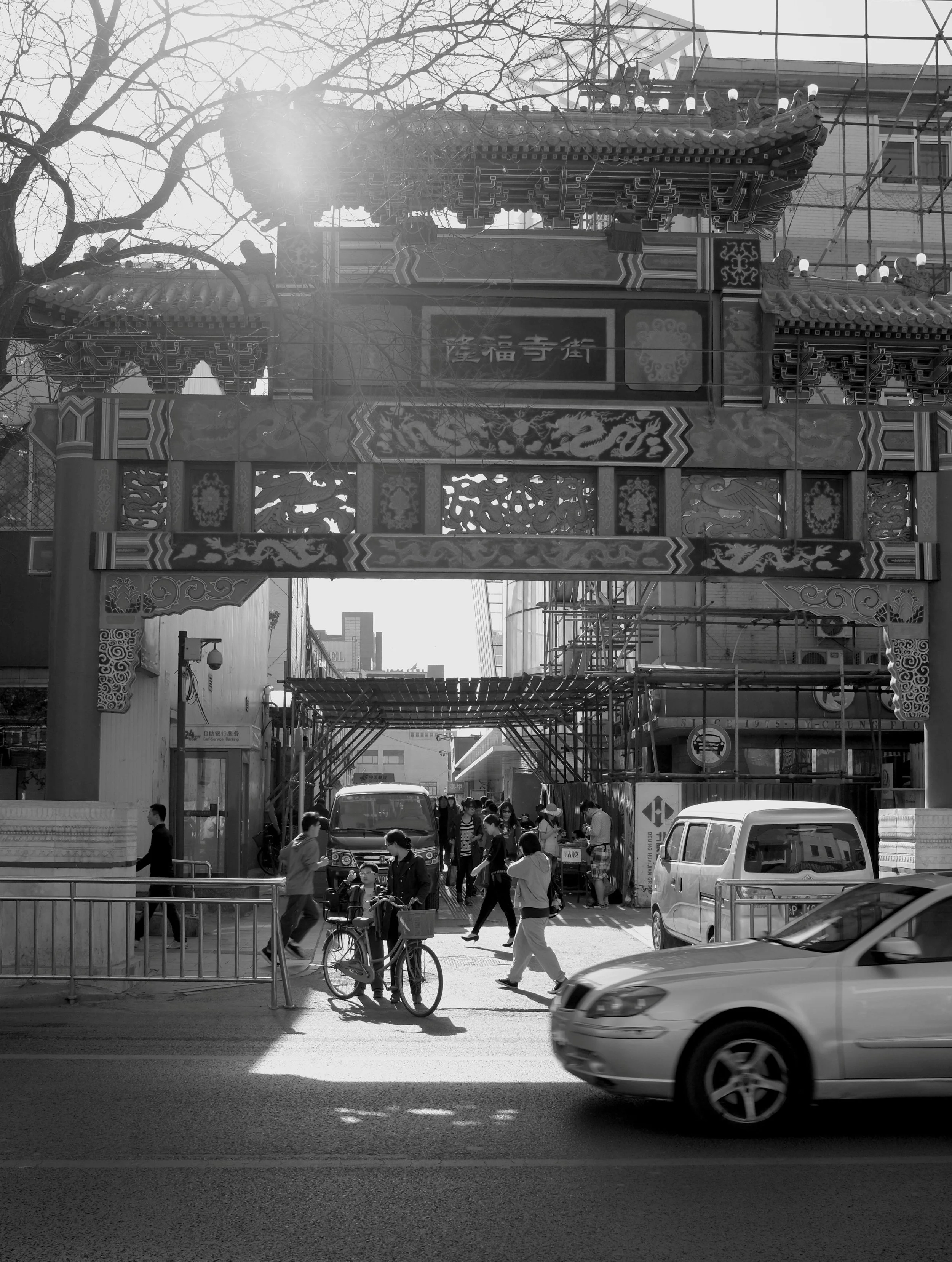 Ein prunkvolles, traditionelles Tor über einer belebten Straße in Peking. Die Lichtstimmung fängt den Kontrast zwischen historischem Erbe und modernem Stadtverkehr (Bewegungsunschärfe) ein. Zeitlose Ästhetik im pvre u Stil.