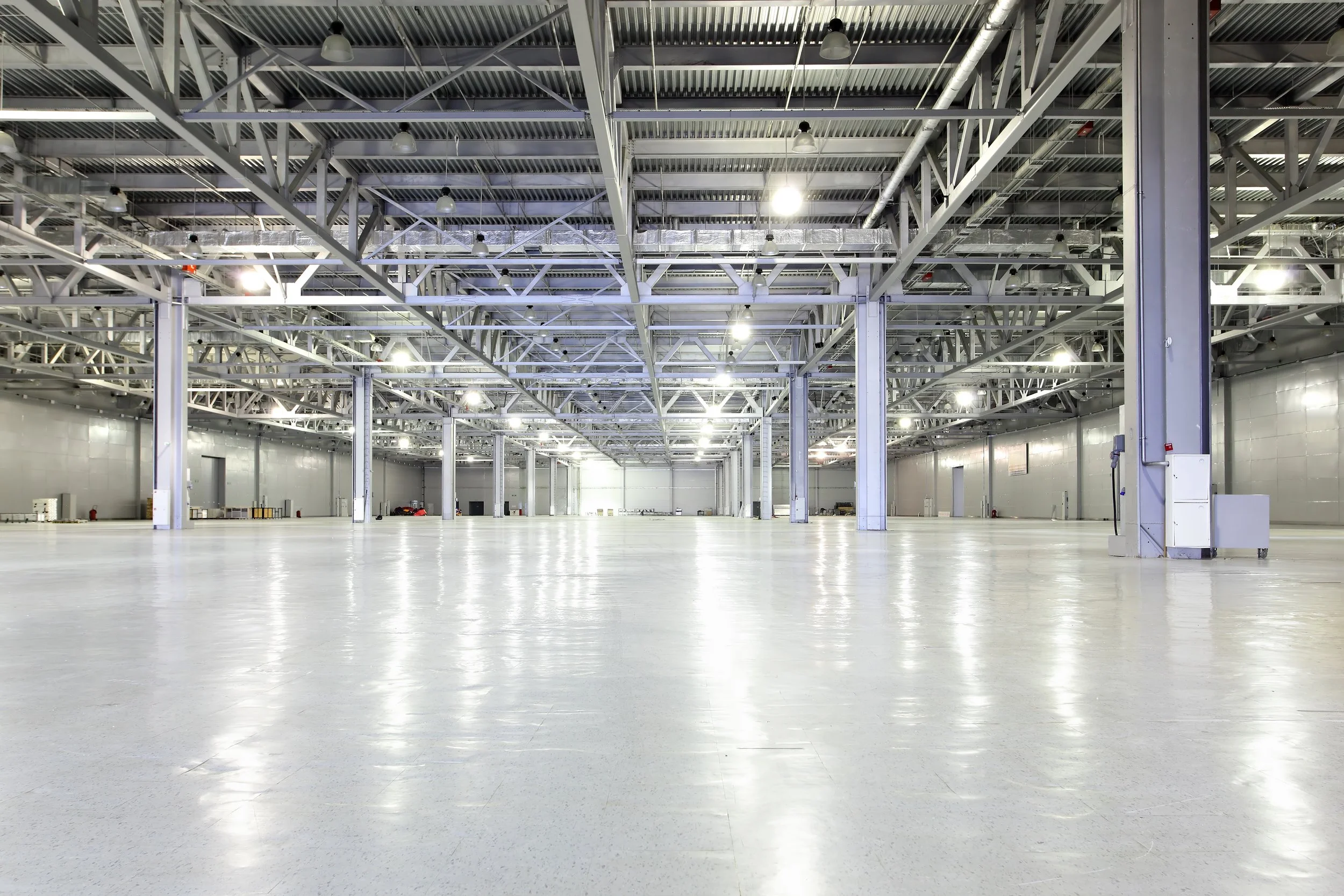 Interior of vacant Portland industrial warehouse with exposed steel structure, high clear height, polished concrete floors, and overhead lighting