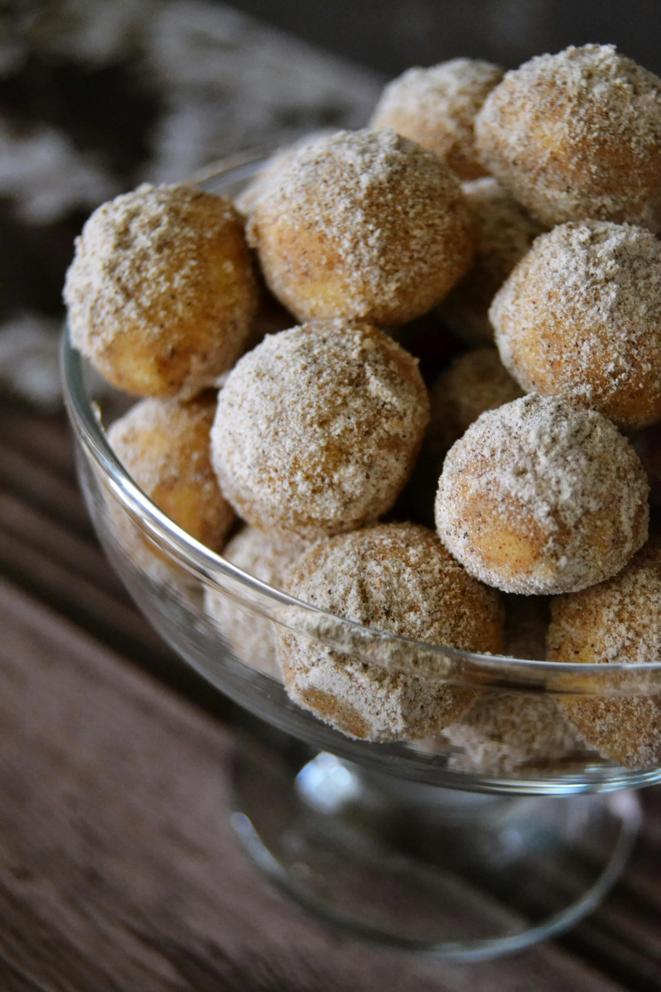 A glass bowl filled with small, round, sugar-coated cookies or cake balls.