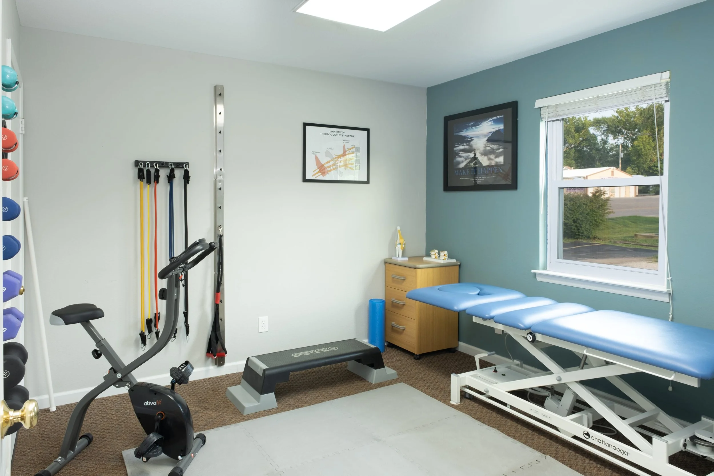Physical therapy room with exercise equipment, a treatment table, and motivational posters.