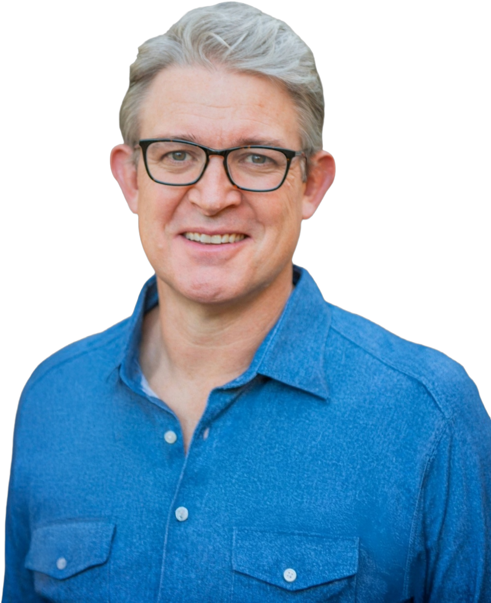 A smiling Caucasian man with gray hair, wearing black glasses and a blue button-up shirt
