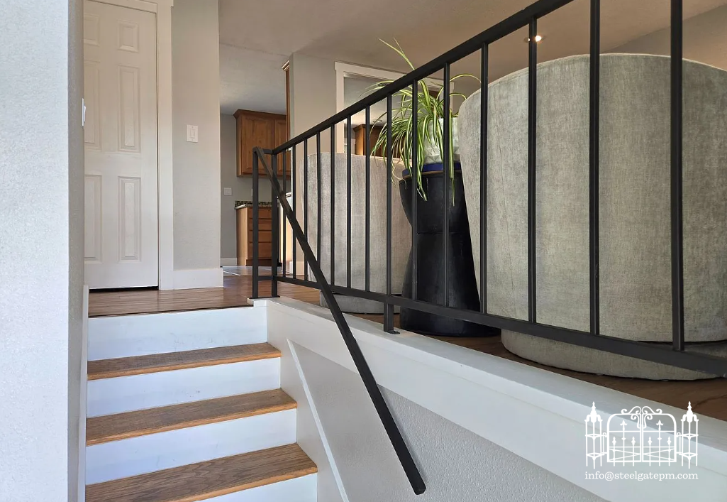 Interior view of a staircase with oak steps and white risers, leading to a living area with beige sofas, a black planter with a green plant, and visible wooden kitchen cabinets in the background.