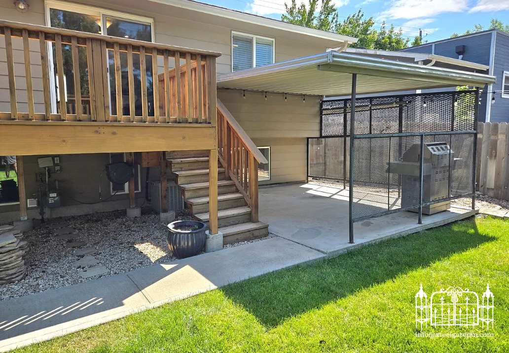 Backyard with a wooden deck, stairs, and an enclosed grilling area with a canopy, surrounded by green grass and a wooden fence.