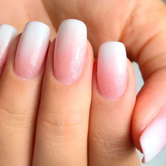 Close-up of well-manicured fingernails with French tips on fingers.