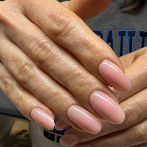Close-up of well-manicured hands with light pink, almond-shaped nail polish.