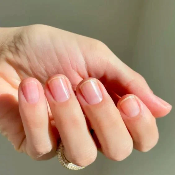 Close-up of a person's hand with neatly trimmed nails and a ring on the ring finger.