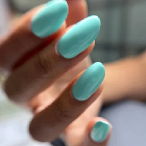 Close-up of a hand showing nails painted in light blue color.