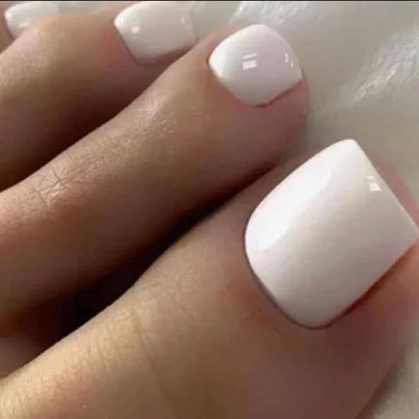 Close-up of neatly painted white fingernails on well-groomed fingers.