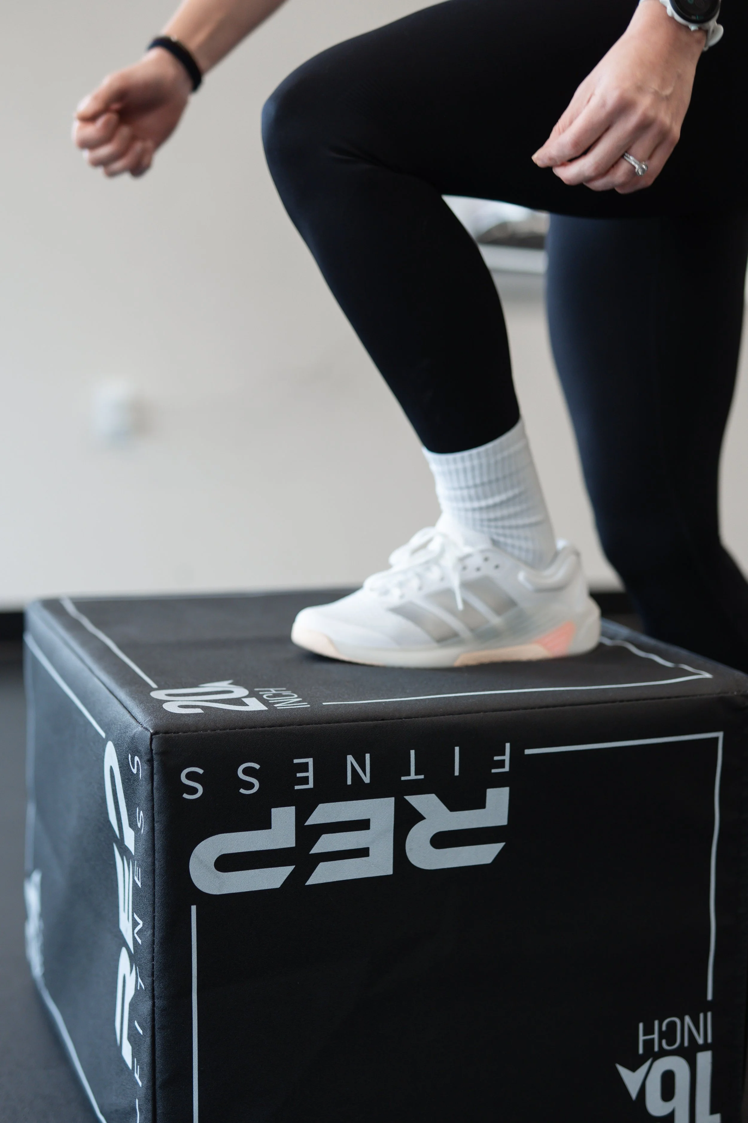 Person stepping onto a black 20-inch box labeled 'RIP Fitness' in a workout or fitness setting.