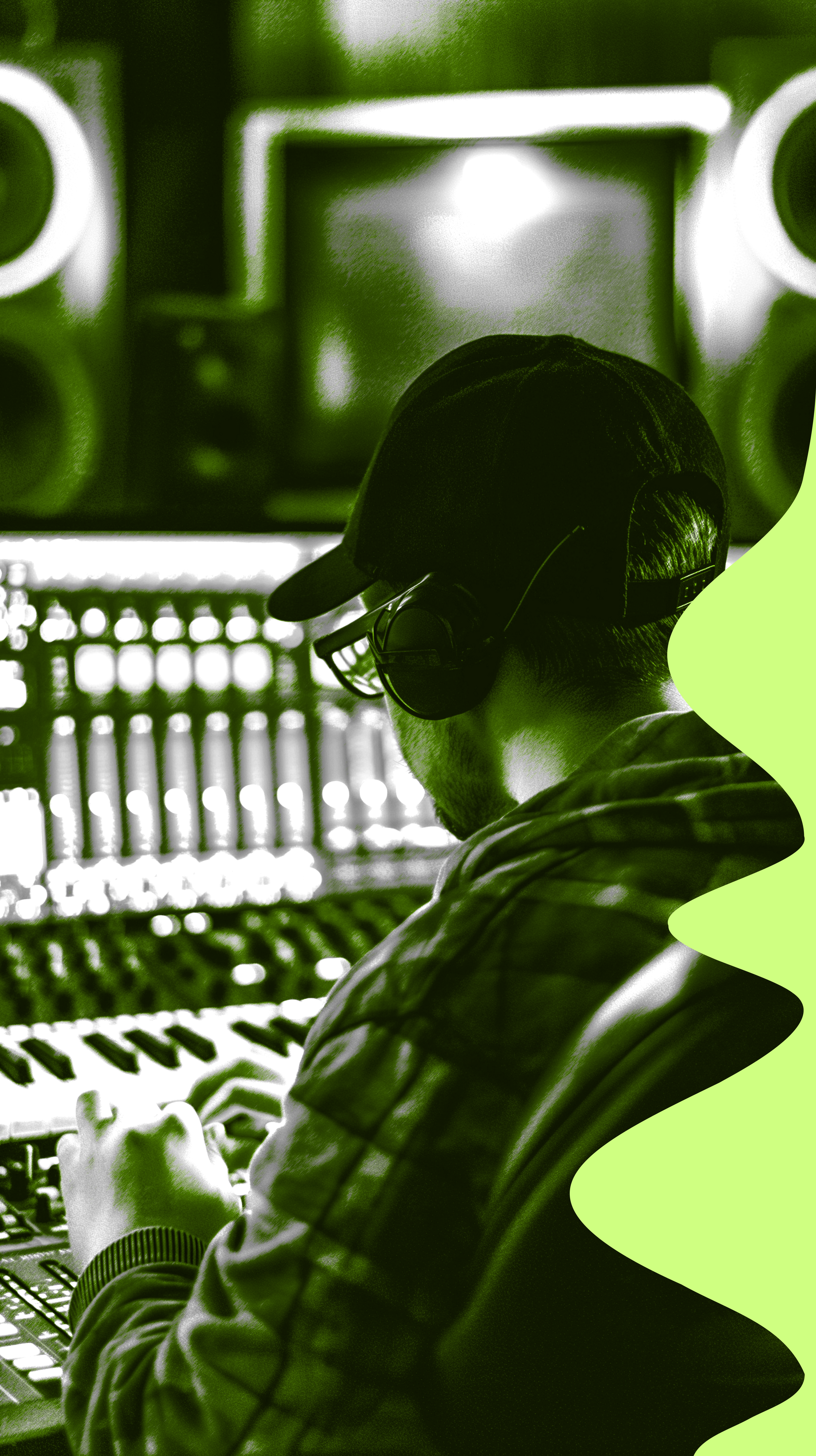 Homem usando fones de ouvido em um estúdio de gravação ou produção musical, com equipamento de áudio ao fundo.