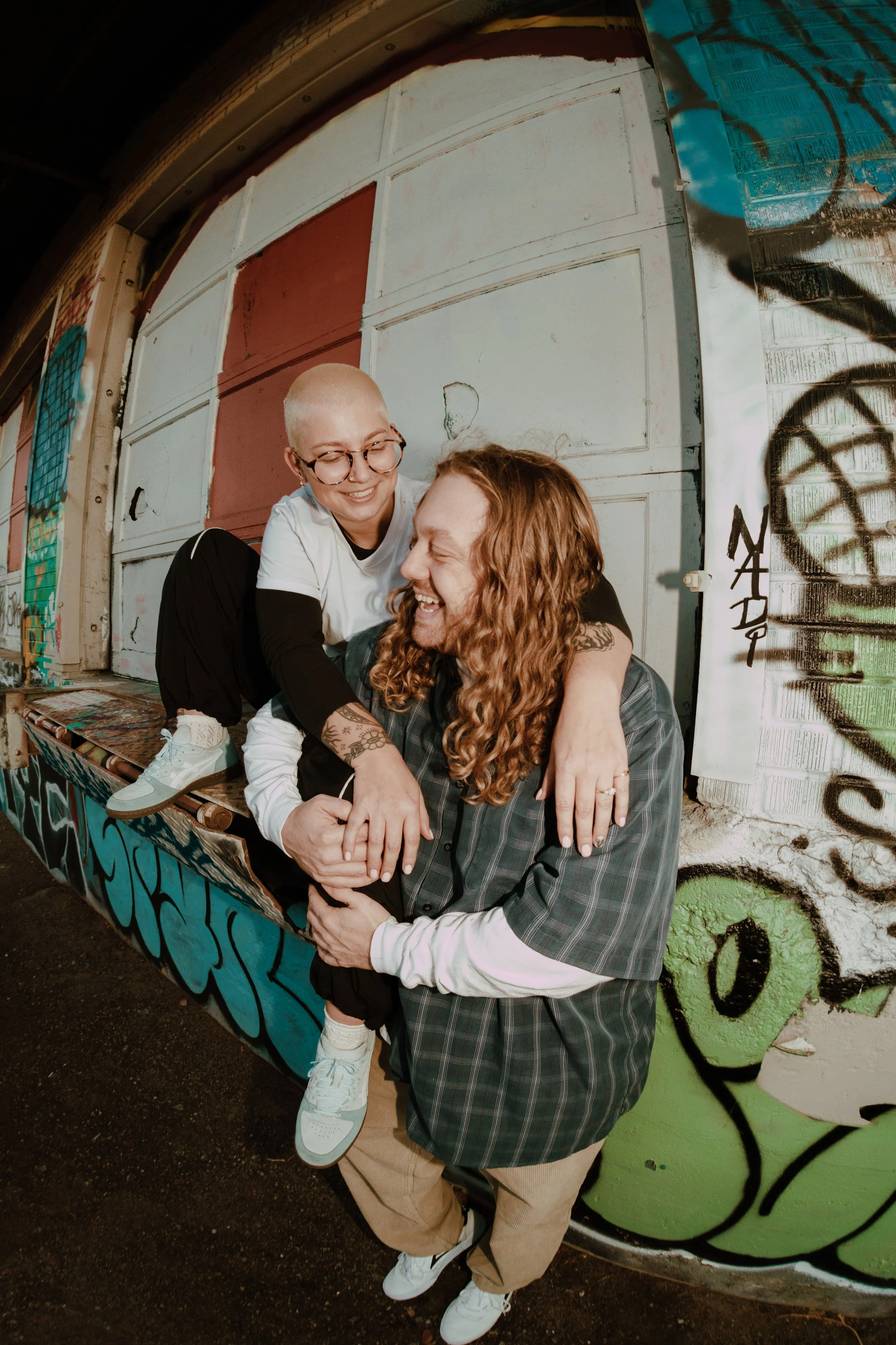 Engagement photo where Anna and Ryder are in front of a graffitied wall.