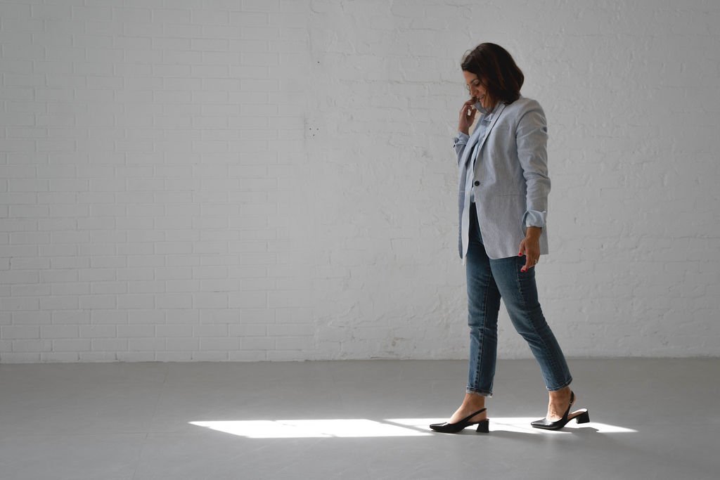 Two people sitting across from each other at a dining table with a laptop, notebook, pens, glasses of water, cups, a dish, and a lamp.