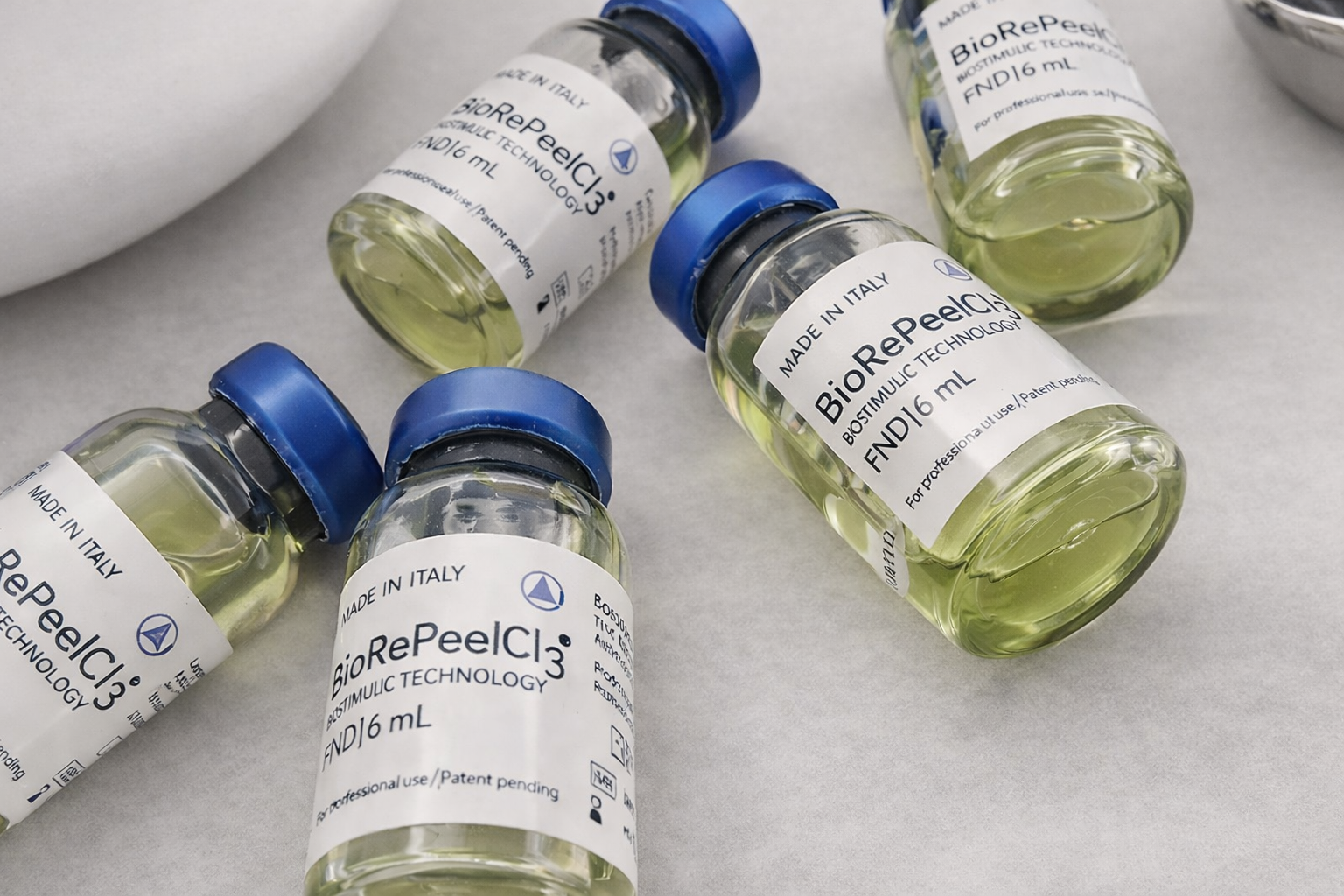 Several small bottles labeled BioRePeel C3 with blue caps, containing a yellowish liquid, placed on a light-colored surface.