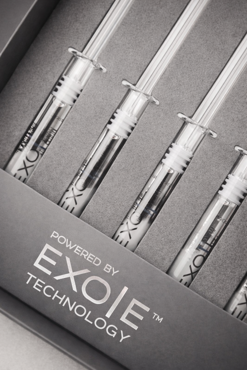 Set of four individual syringe-like devices labeled 'Exo' in a gray box with the text 'Powered by Exo/ie Technology'.