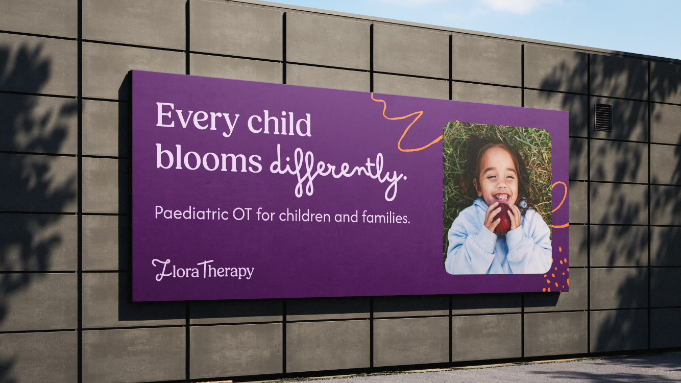 A large purple sign on a gray wall promoting therapy for children, with a photo of a smiling girl holding an apple, and decorative orange lines and dots.