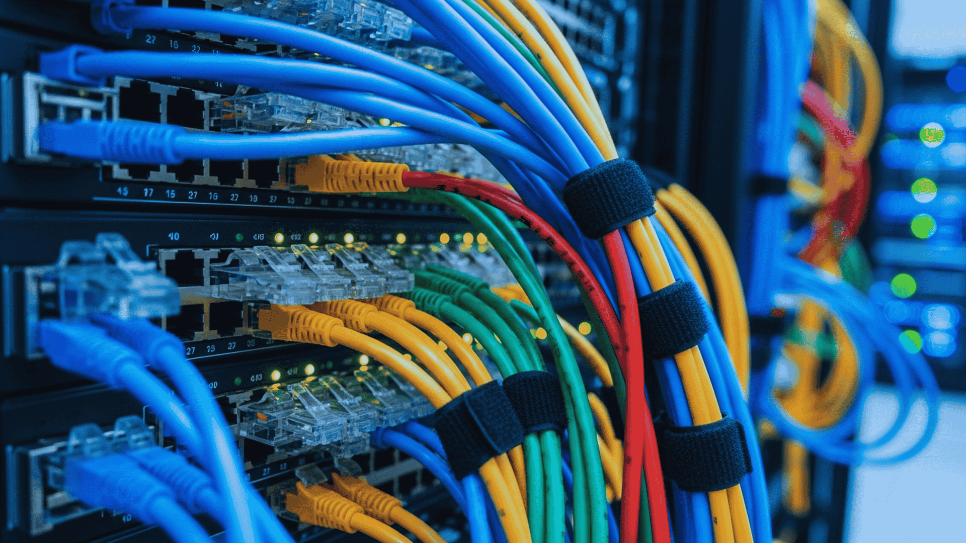Colorful network cables plugged into a server rack, secured with black velcro straps.